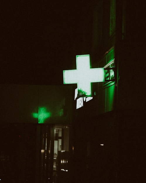 A pharmacy sign glows green at night.