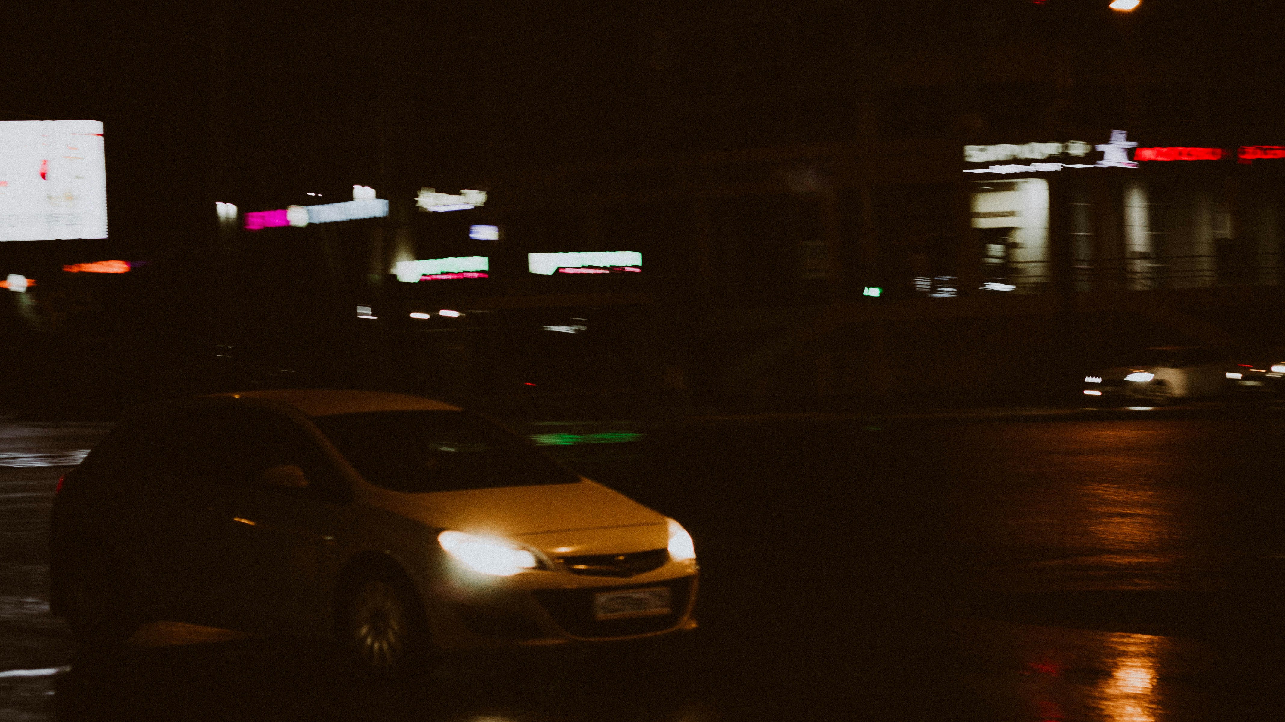 A car drives on a dark, rainy night.