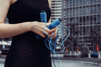 A woman holds a jump rope outdoors.