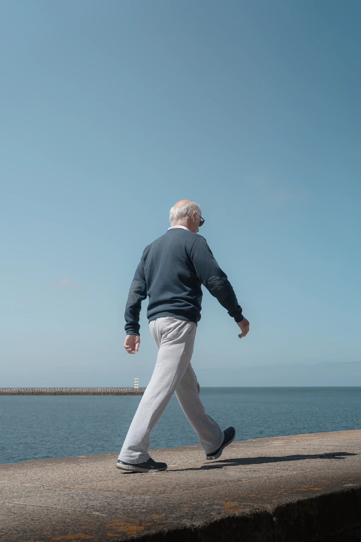 Mature man walking by sea — knees and tendons that work