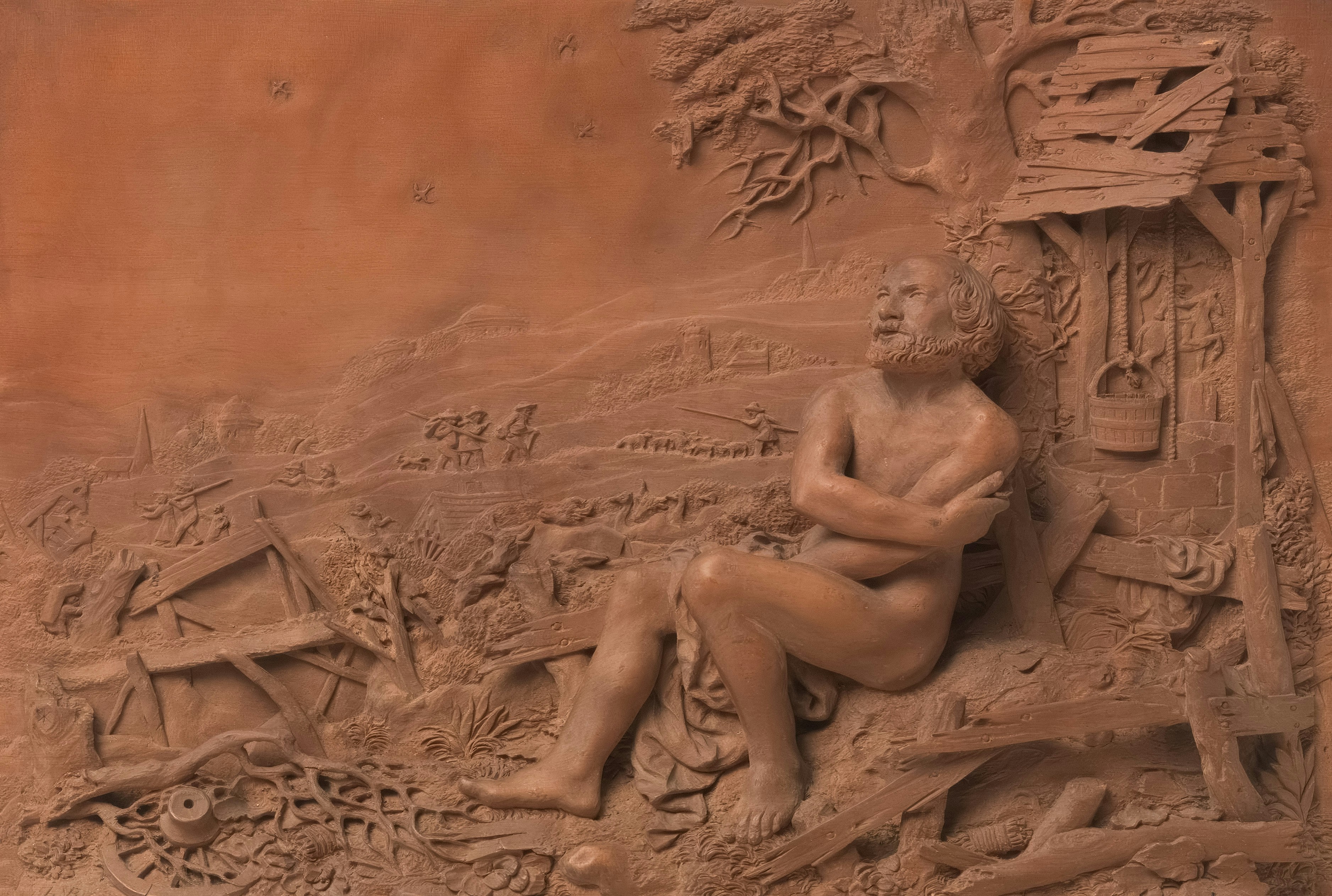 A terracotta relief of a man sitting under a tree.