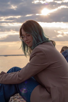 Young woman with teal hair by the ocean at sunset