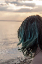 Woman with teal highlights looking at the ocean