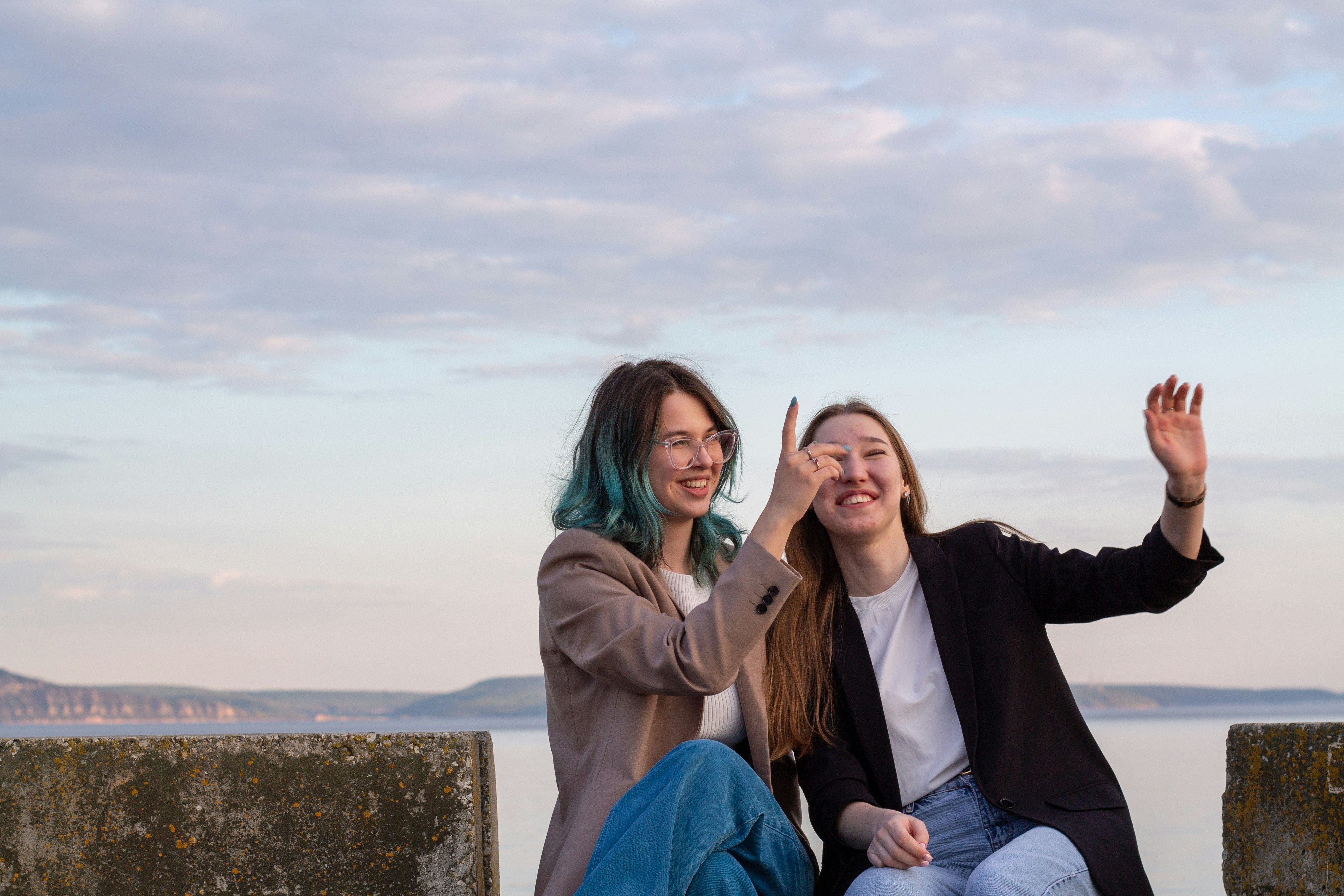 Two women laughing and pointing at the sky.
