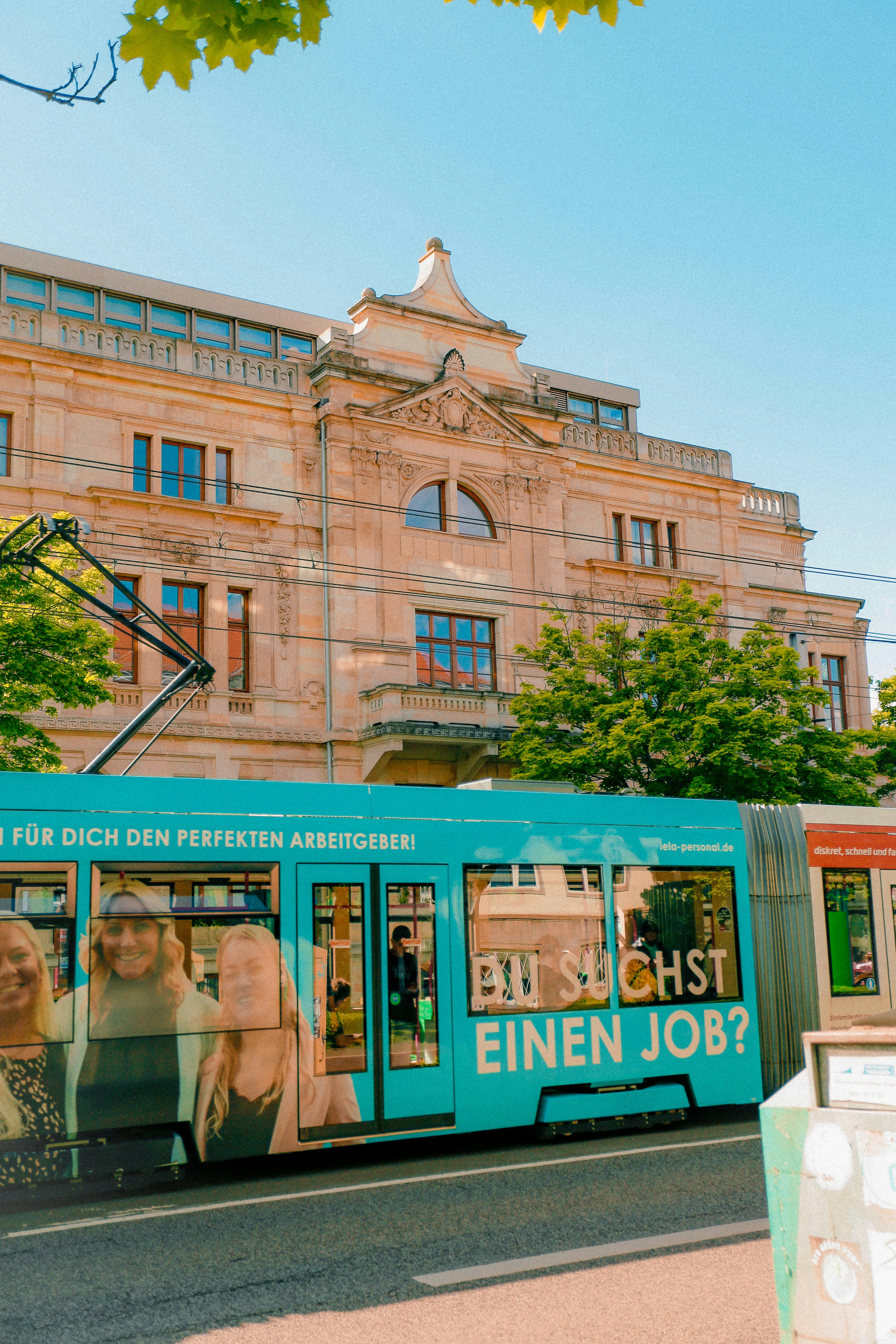 A blue tram is in front of a beautiful building.