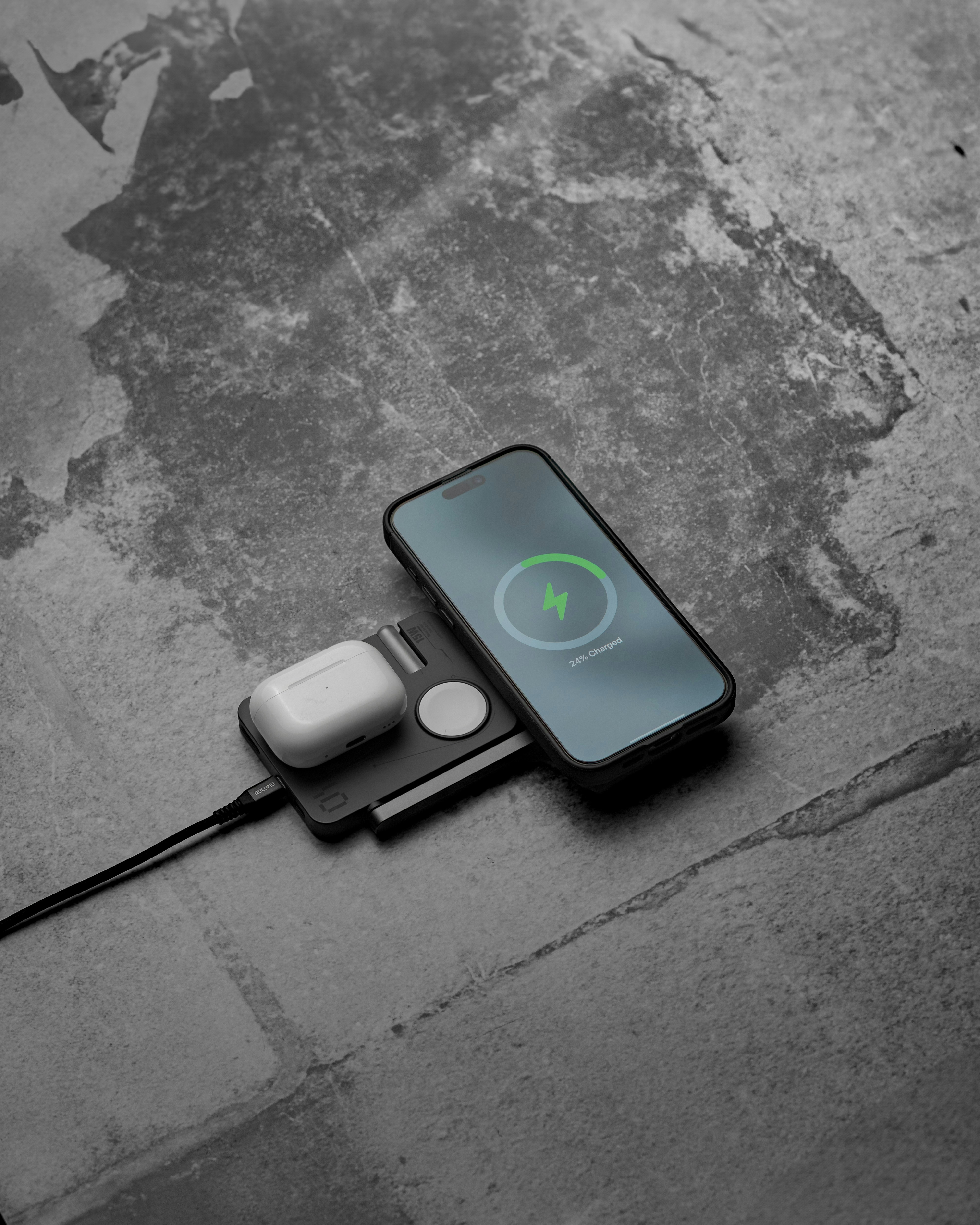 Telefone, relógio e fones de ouvido carregando em um pad.