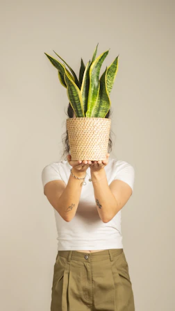 A woman holds a plant in front of her face.