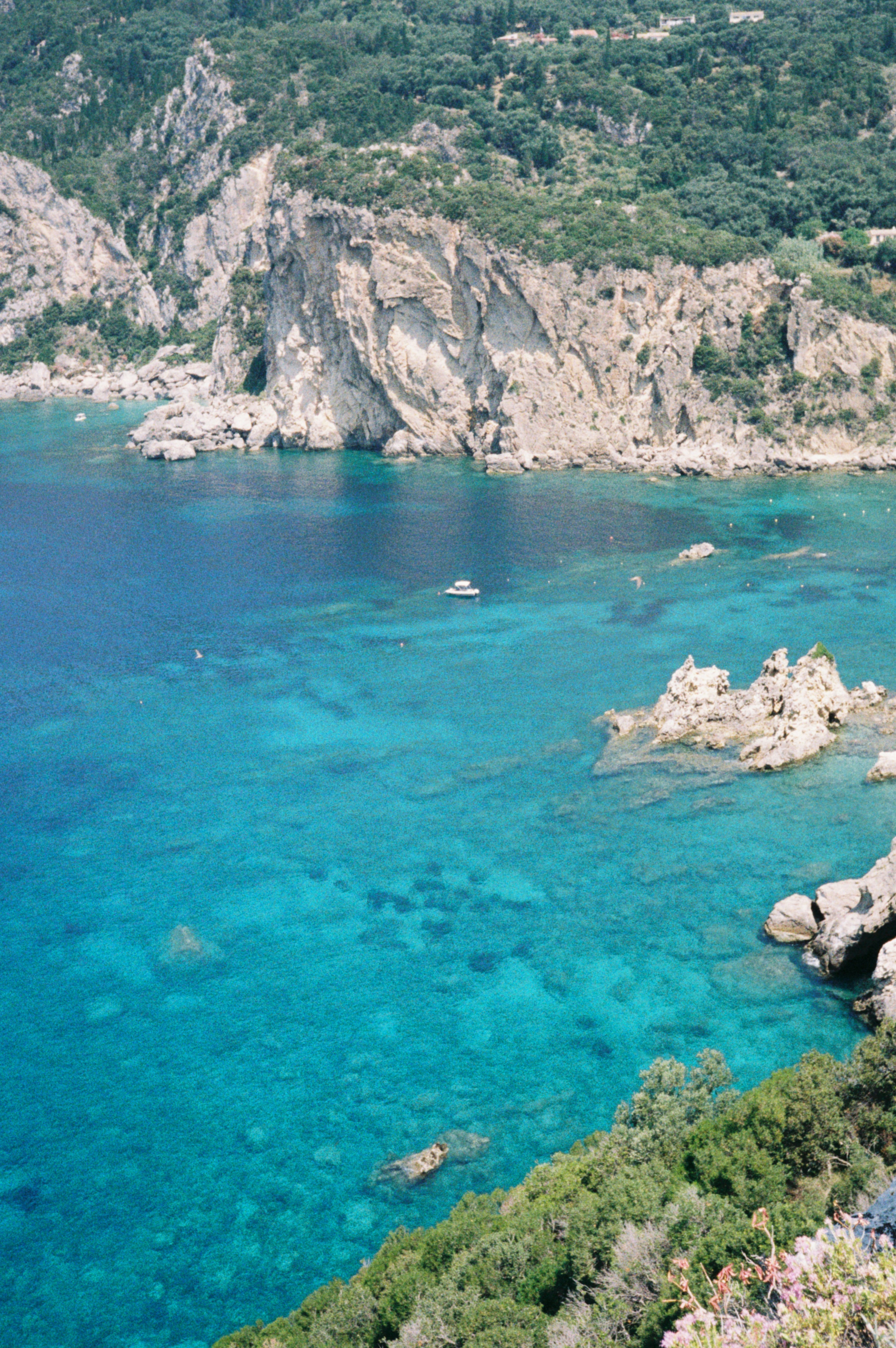 A boat floats in the turquoise sea.