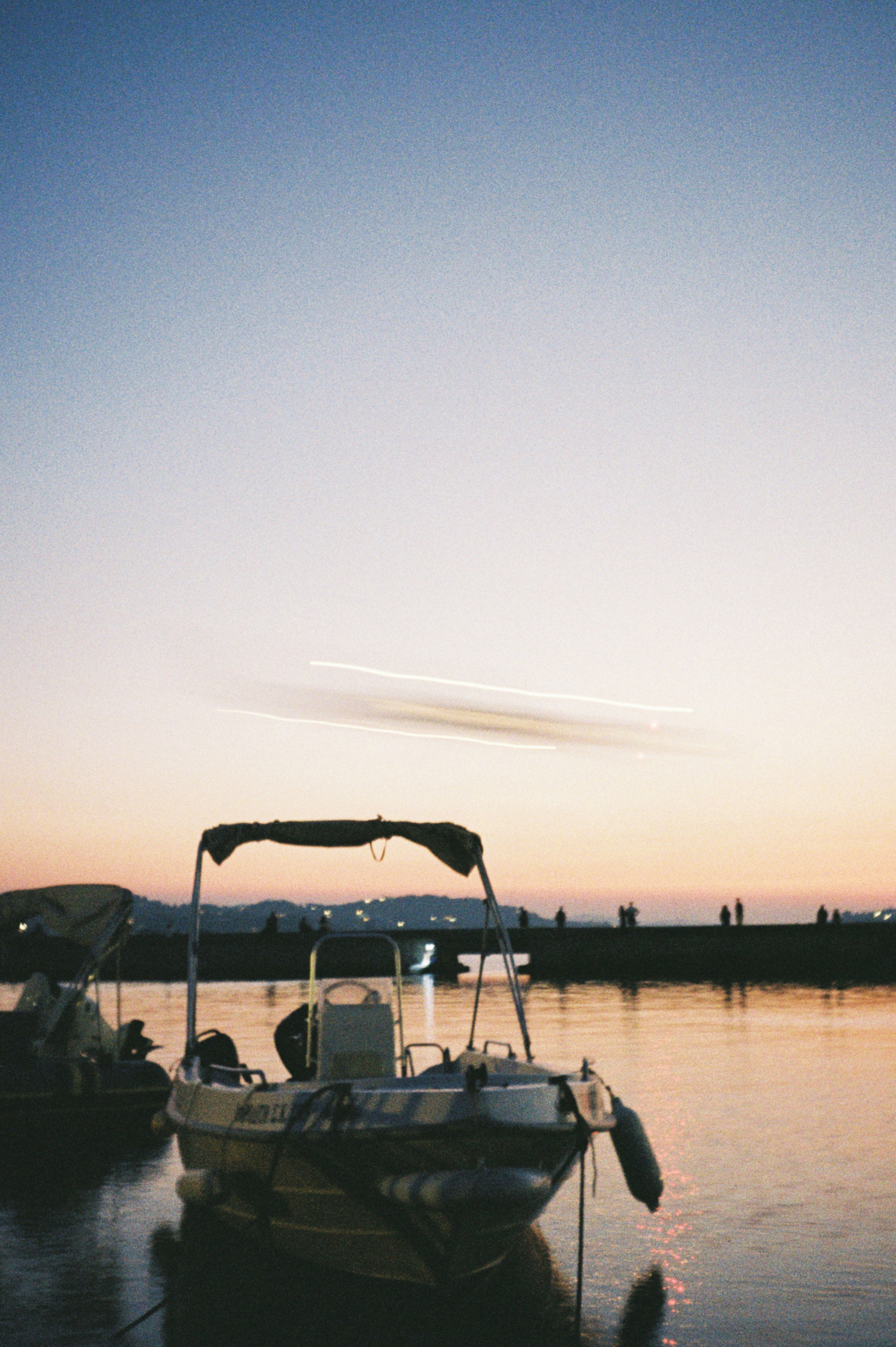 Boats rest peacefully at dusk on the water.