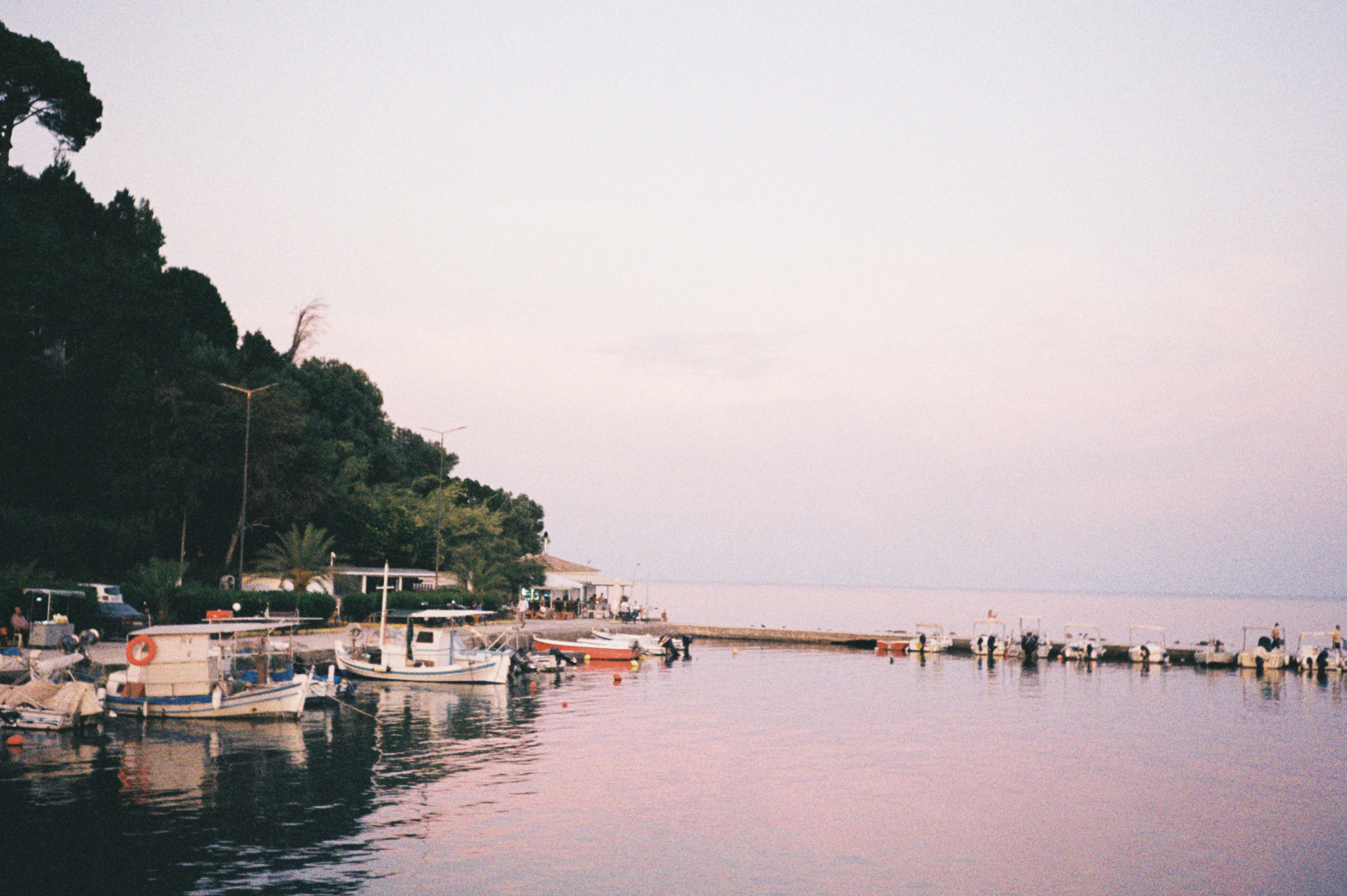 Boats dock on a tranquil bay at dusk.