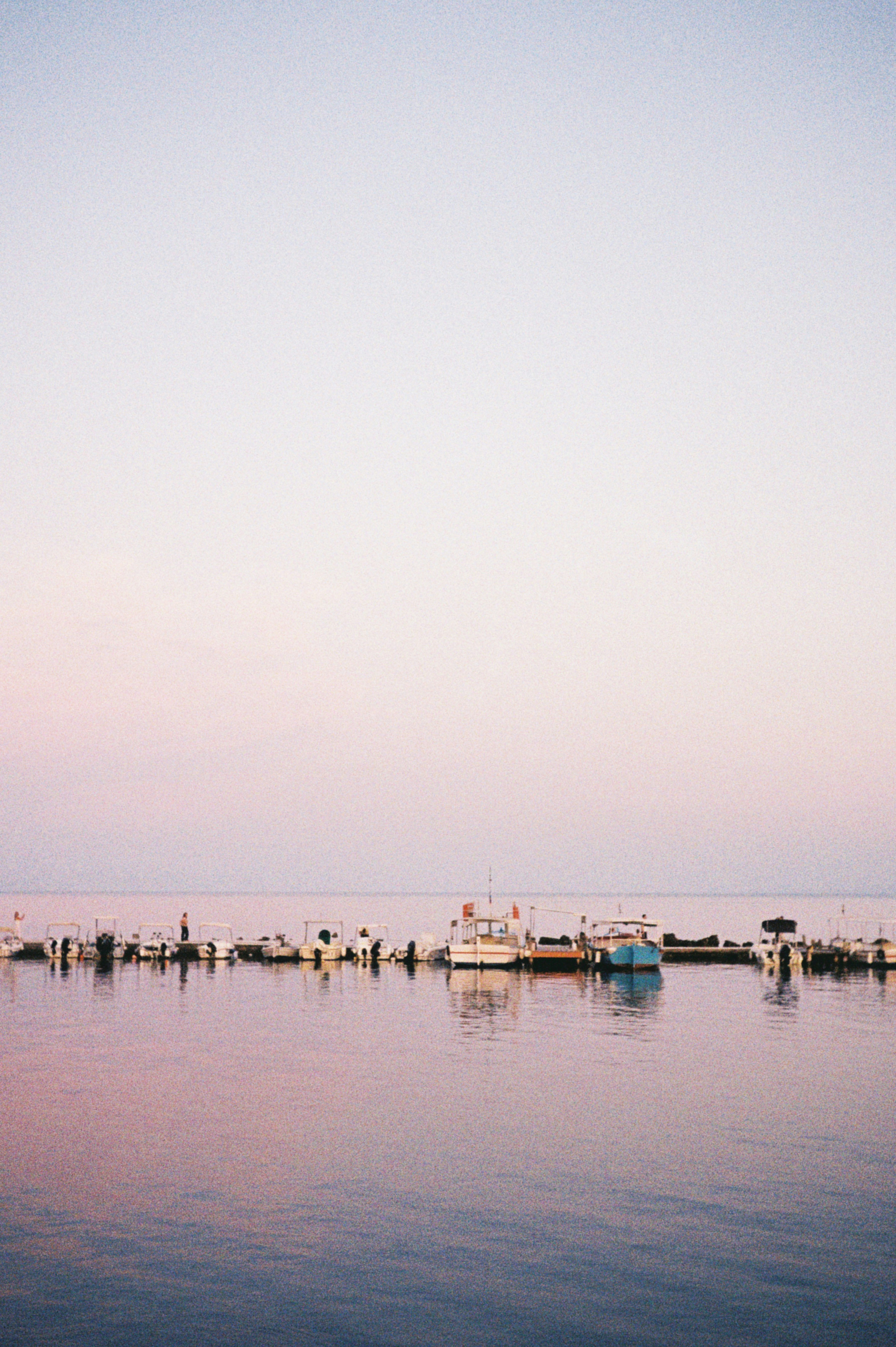 Boats are docked on serene water at sunrise.