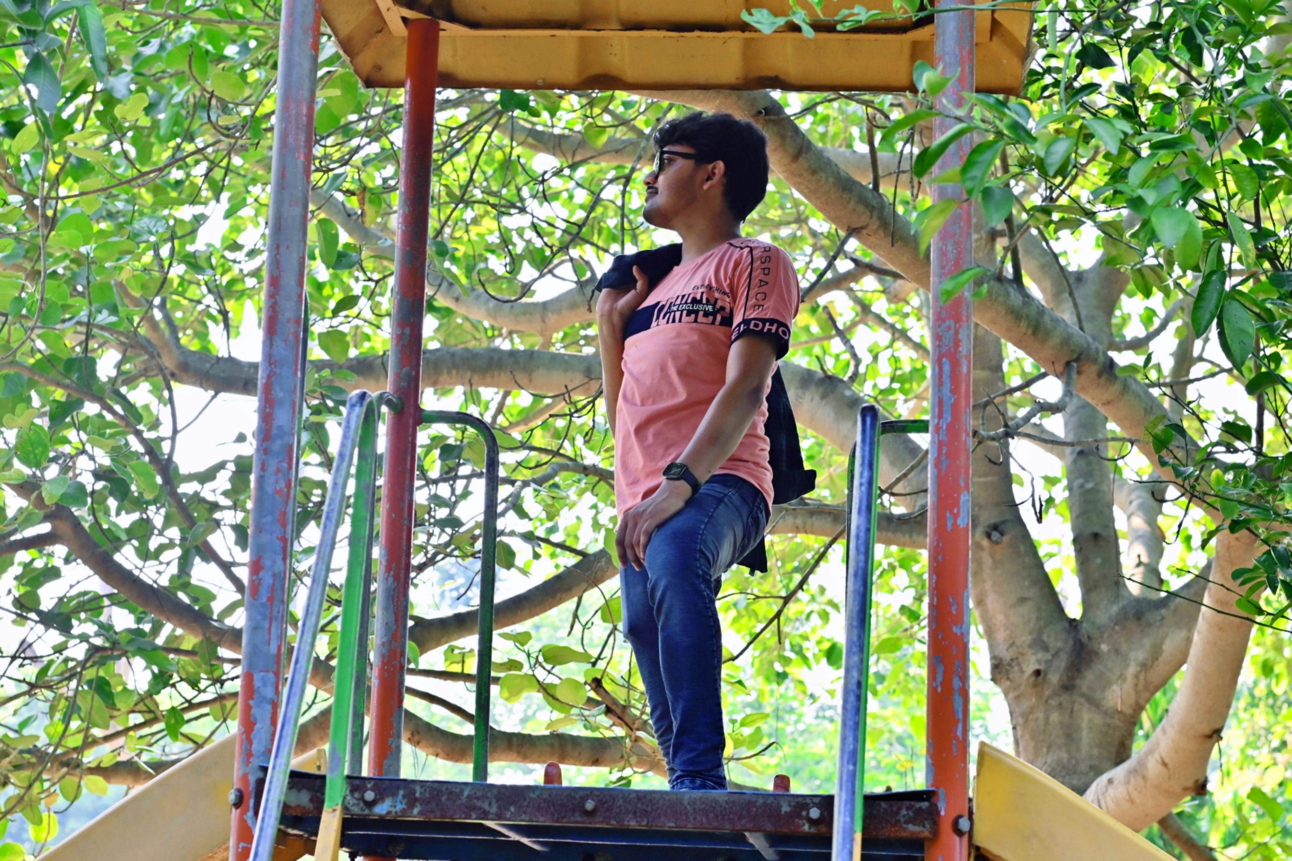屋外の遊具の上に立つ若い男性。