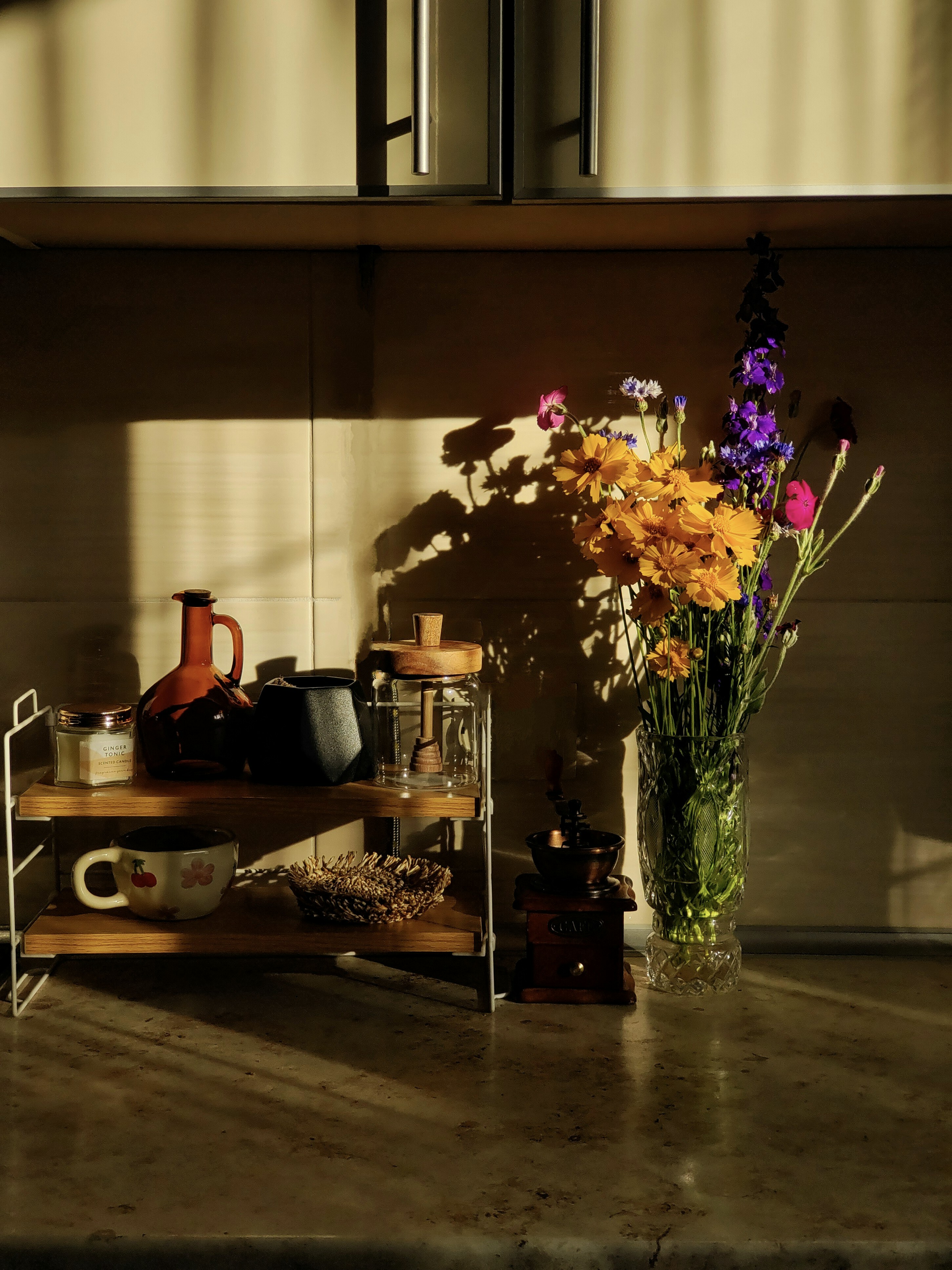 Las flores y los accesorios de café se sientan en la cocina iluminada por el sol.