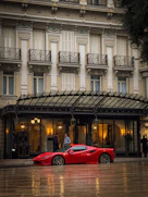 A red ferrari sits in front of a hotel.