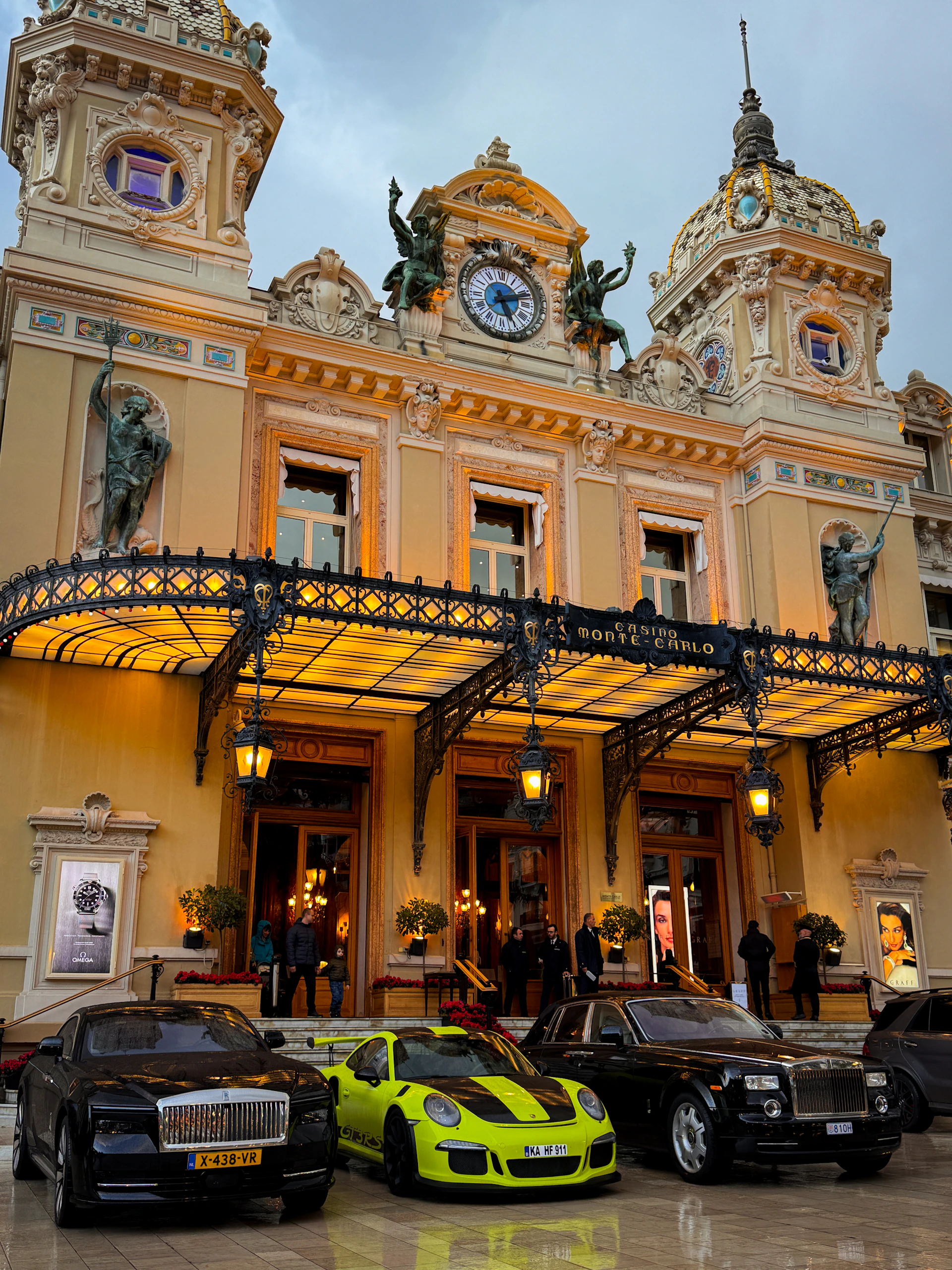 Luxury cars parked in front of a grand building.