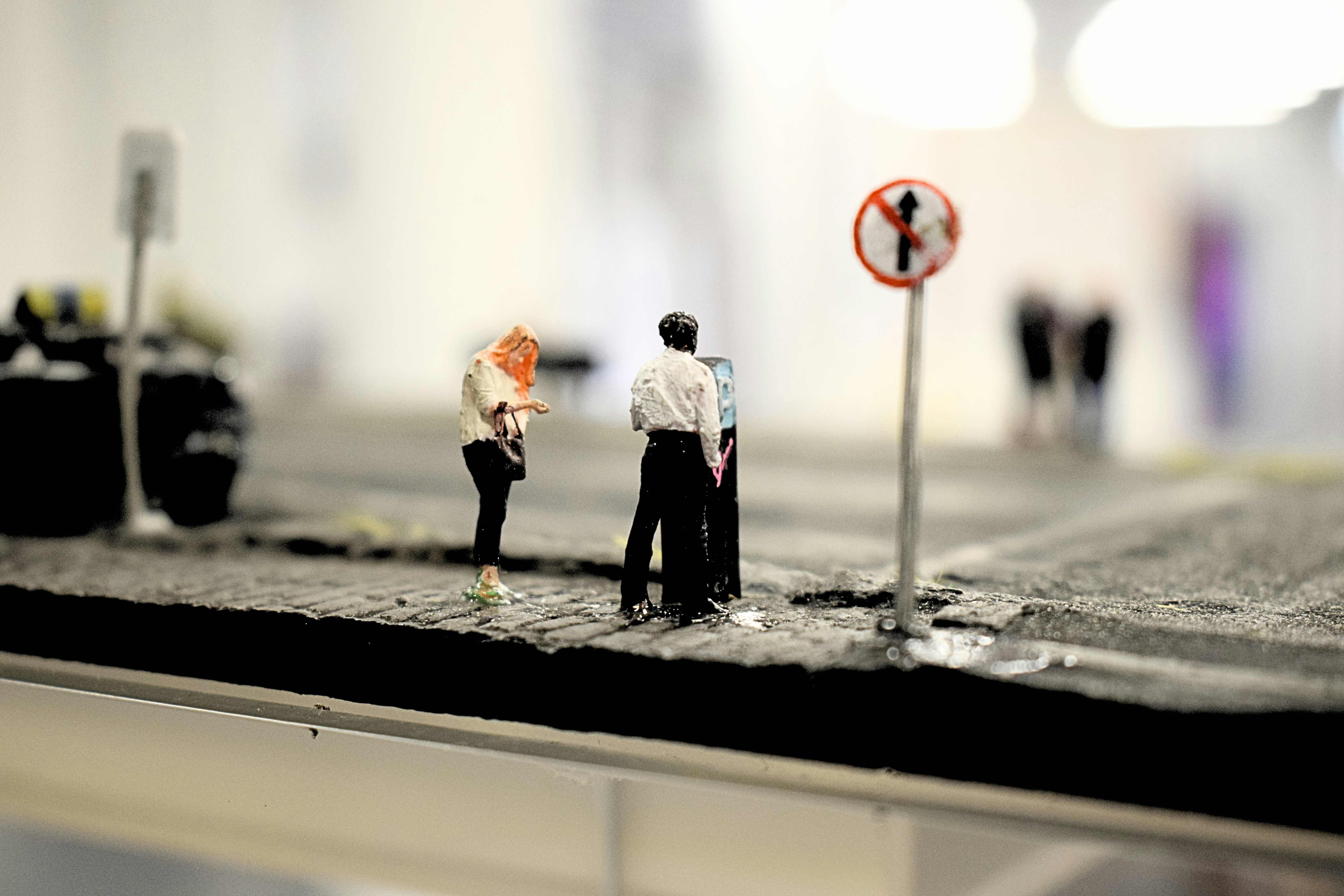 Miniaturmenschen stehen in der Nähe eines Linksabbiegeverbotsschilds.