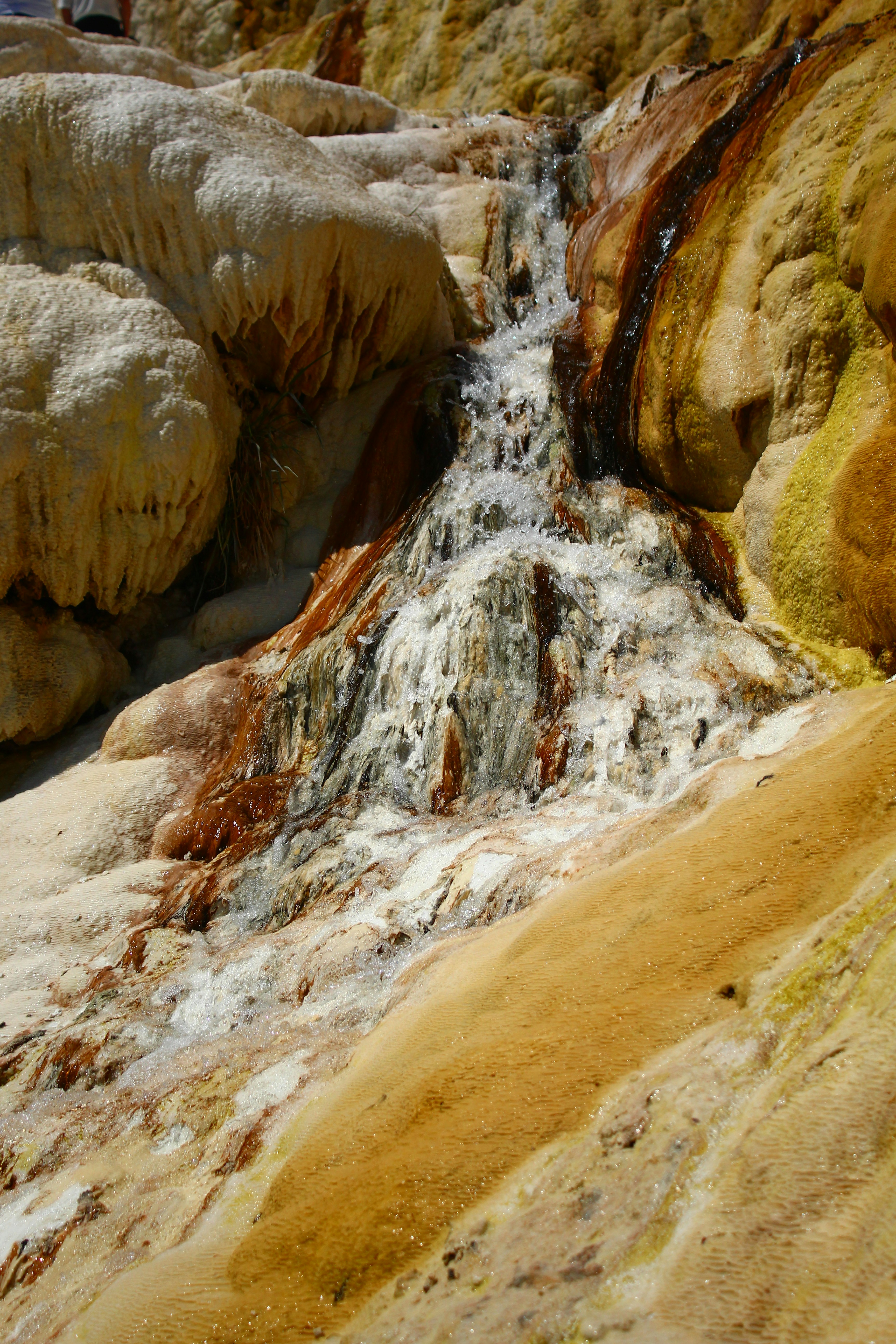 A small, colorful waterfall cascades over the rock.