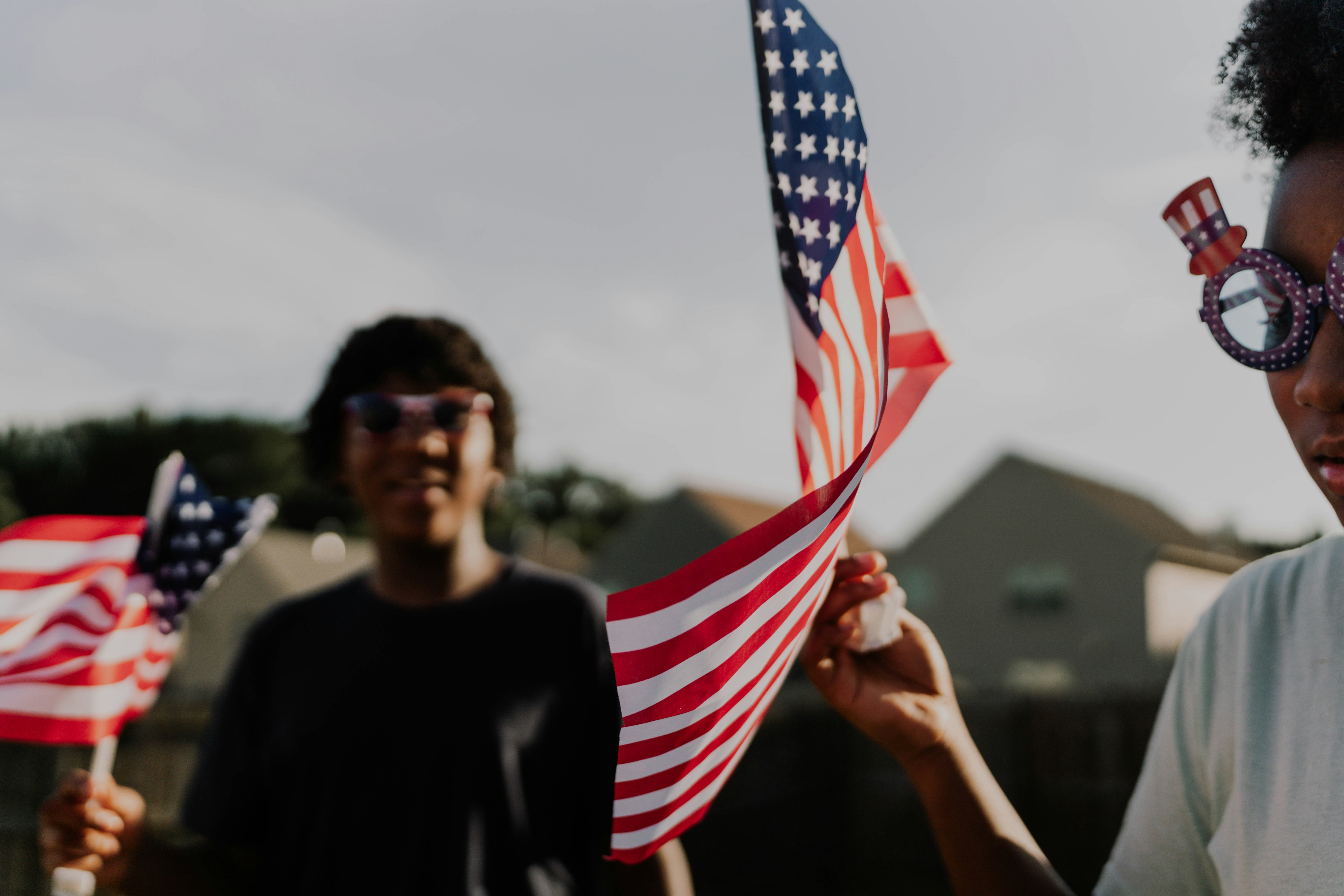 People celebrate with american flags and patriotic glasses.