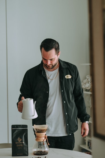 Man is brewing coffee with a pour-over method.