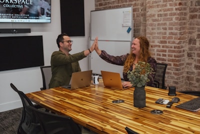 Two people high-fiving in a meeting room.