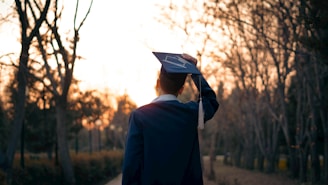 Graduating student celebrates on a path at sunset.