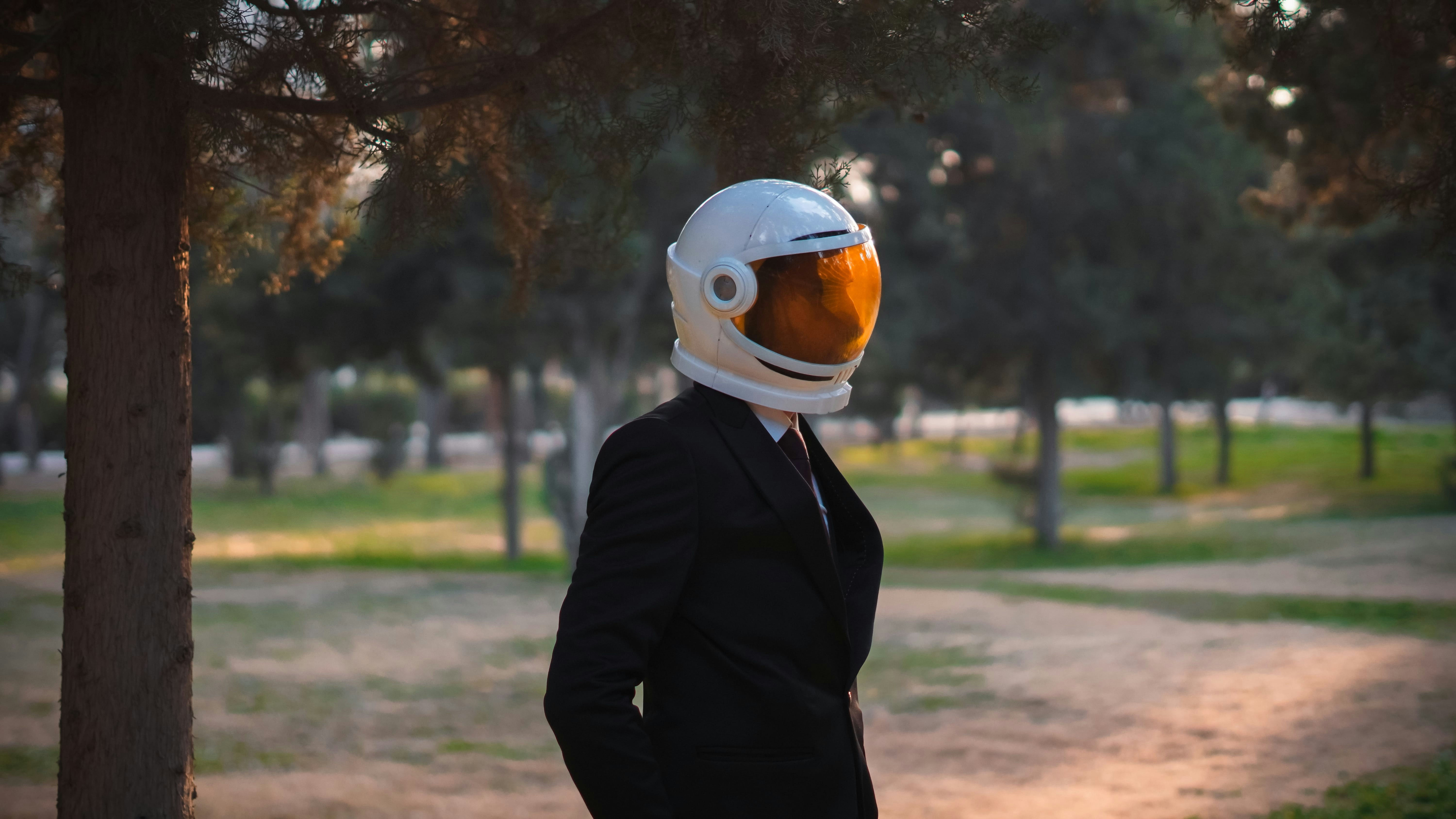 Person wearing a space helmet stands in a park.
