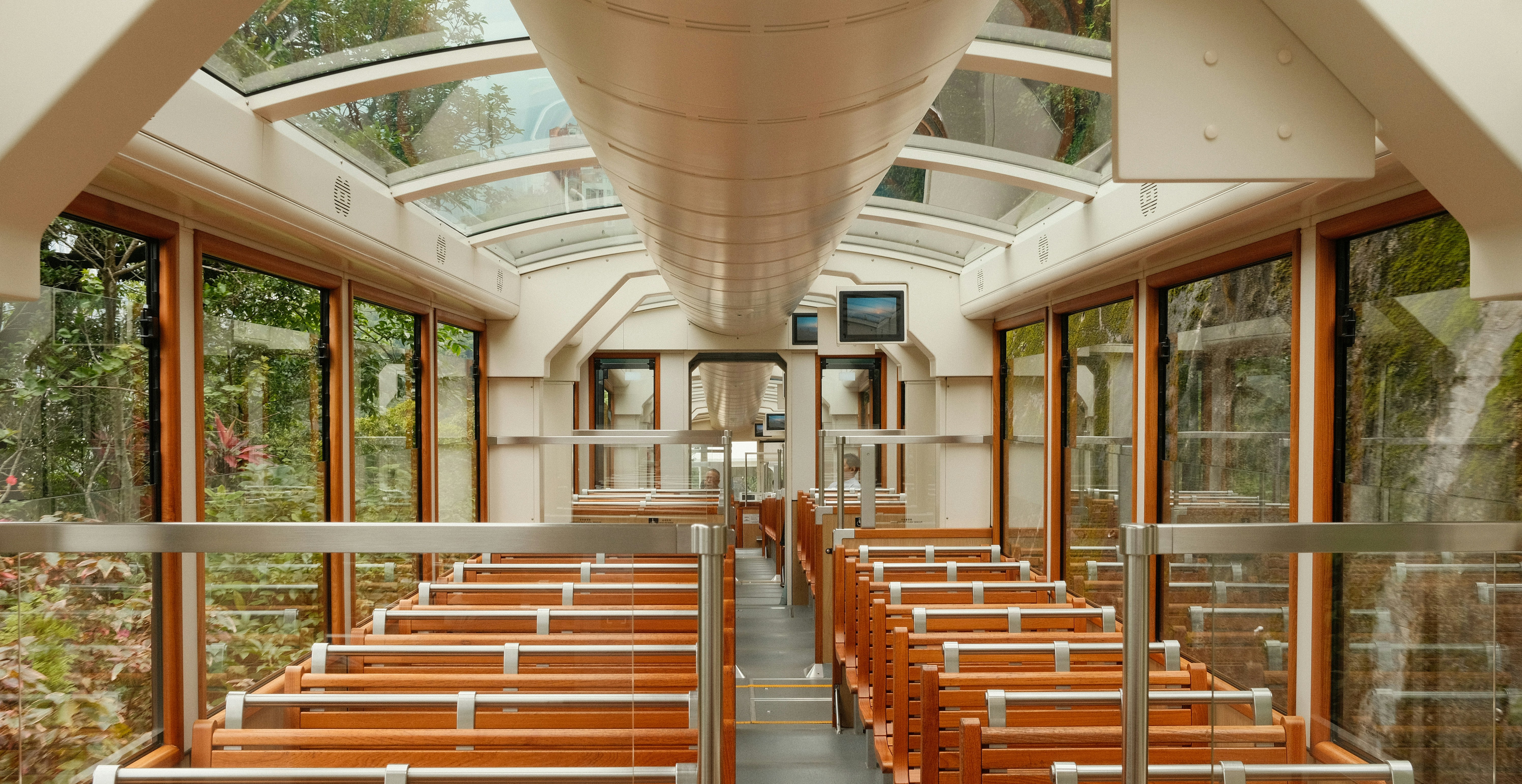 Inside a boat with glass windows and wooden seats.