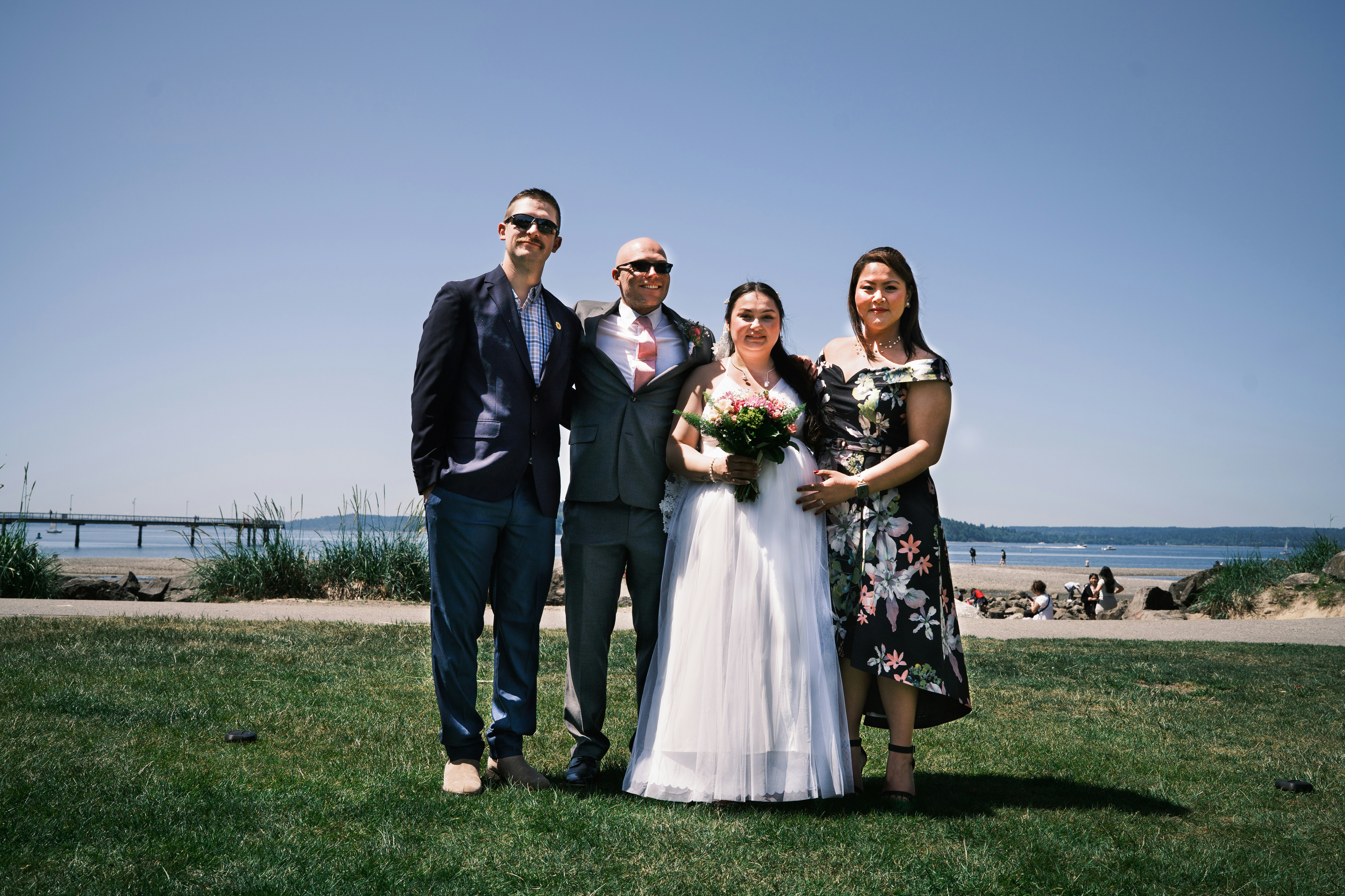 Una feliz fiesta de bodas posa al aire libre en un día soleado.