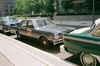 Vintage taxis are parked along a city street.