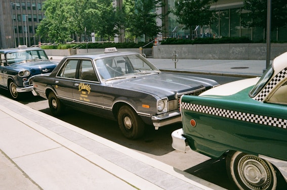 Vintage taxis are parked along a city street.
