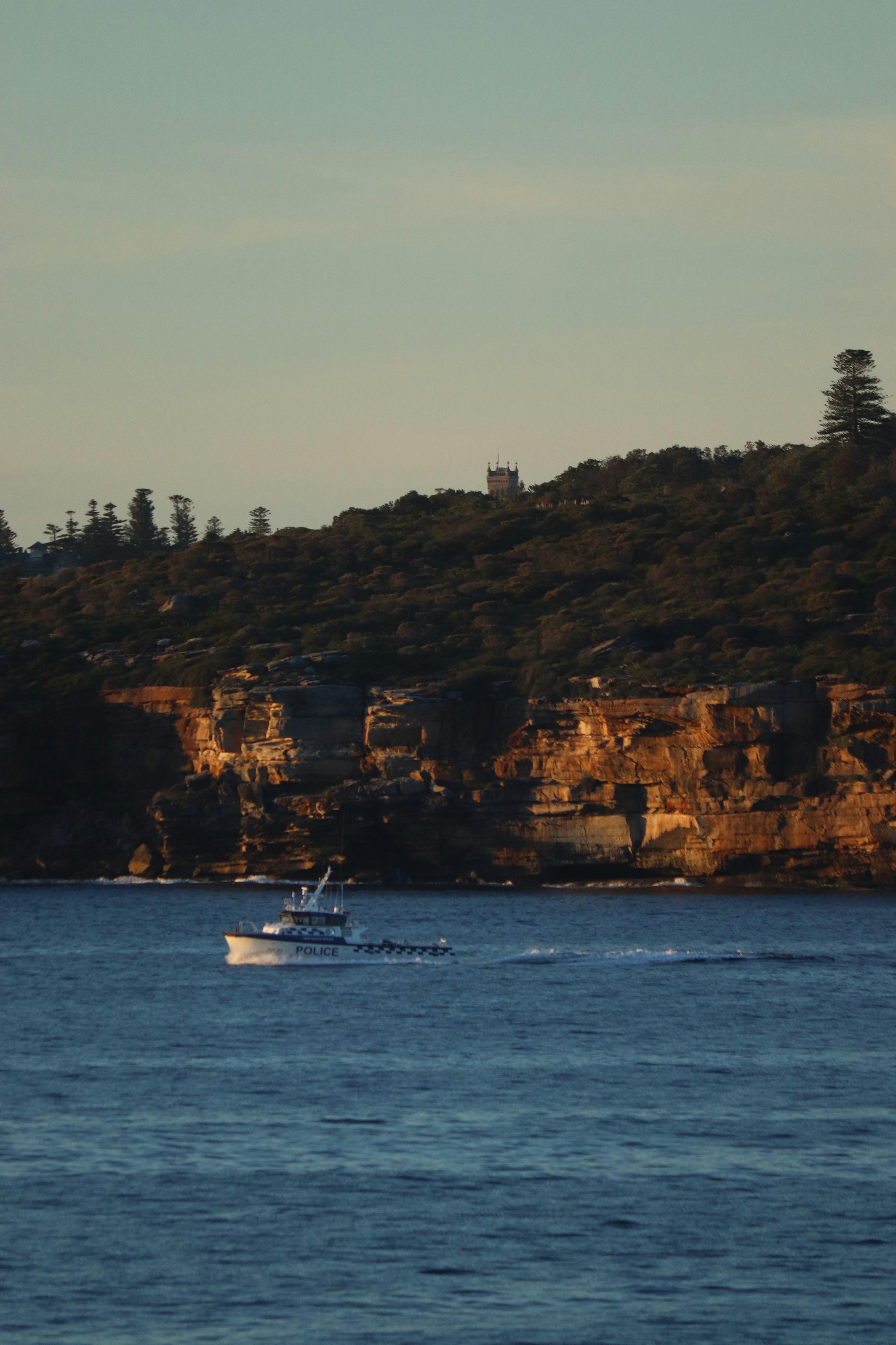 Das Boot segelt bei Sonnenuntergang vor den Klippen.