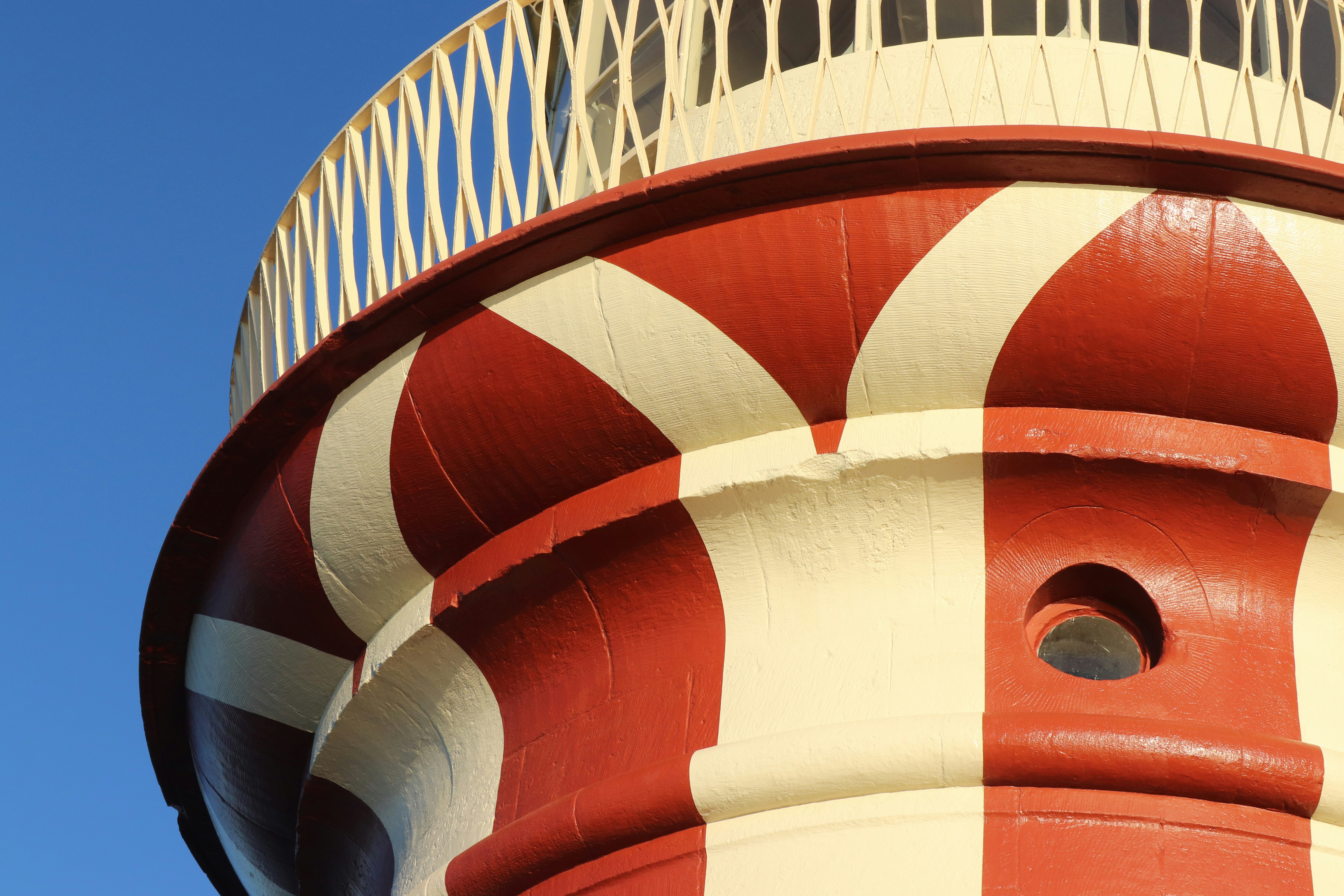 Rot-weiße Leuchtturmdetails vor einem strahlend blauen Himmel.