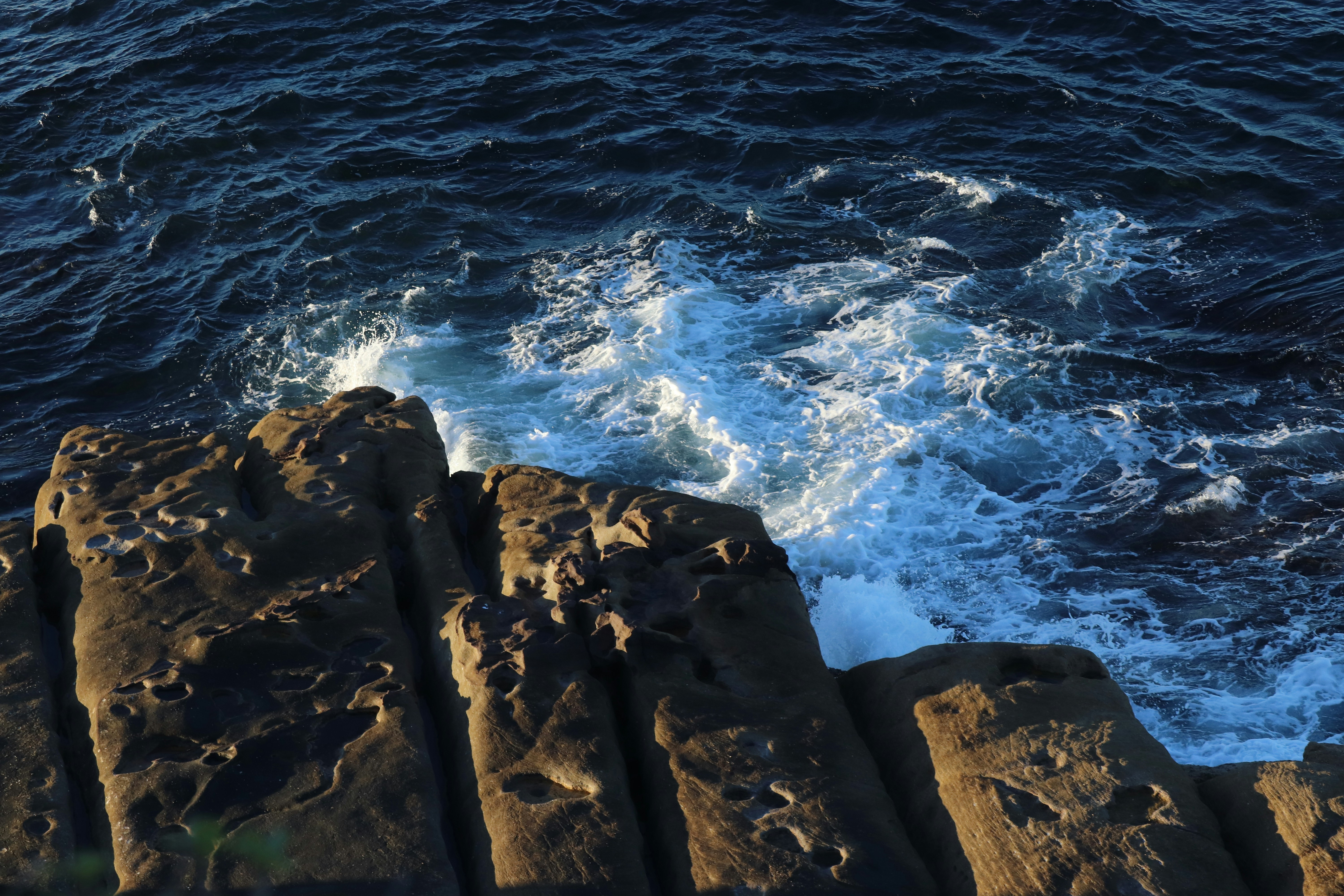 Wellen schlagen gegen zerklüftete Felsen am Meer.