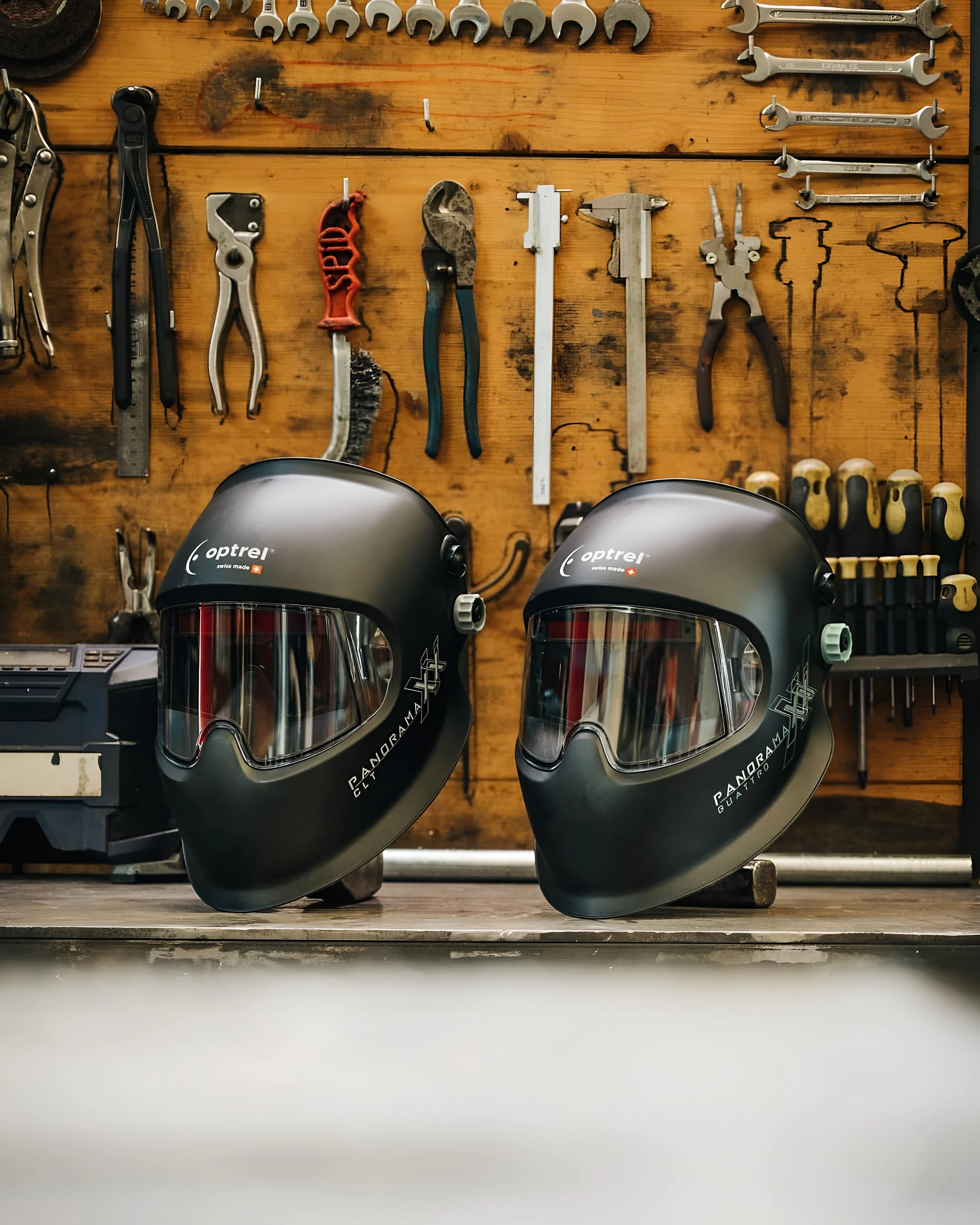 Welding helmets stand before workshop tools.