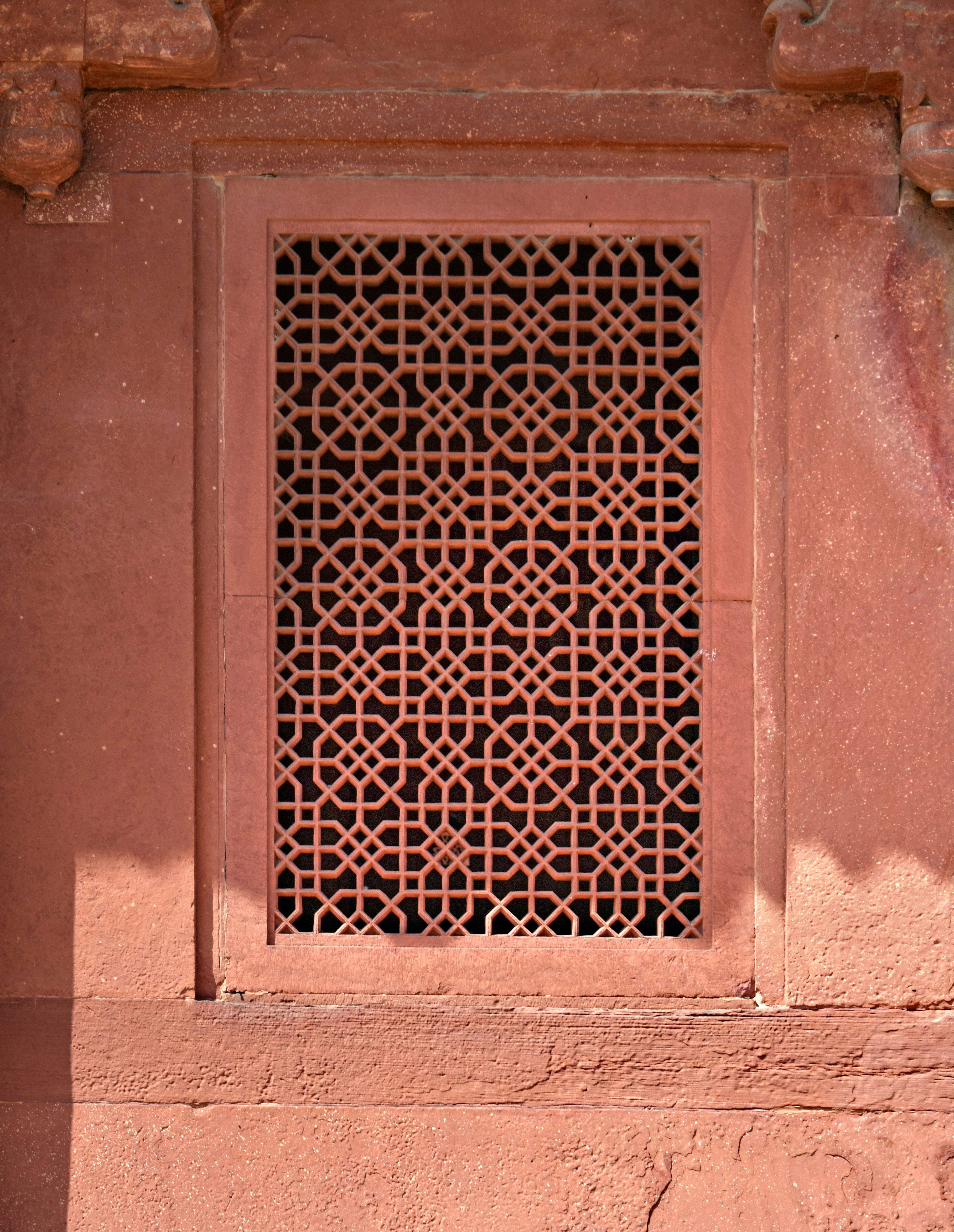 An ornate, red-hued window grille.