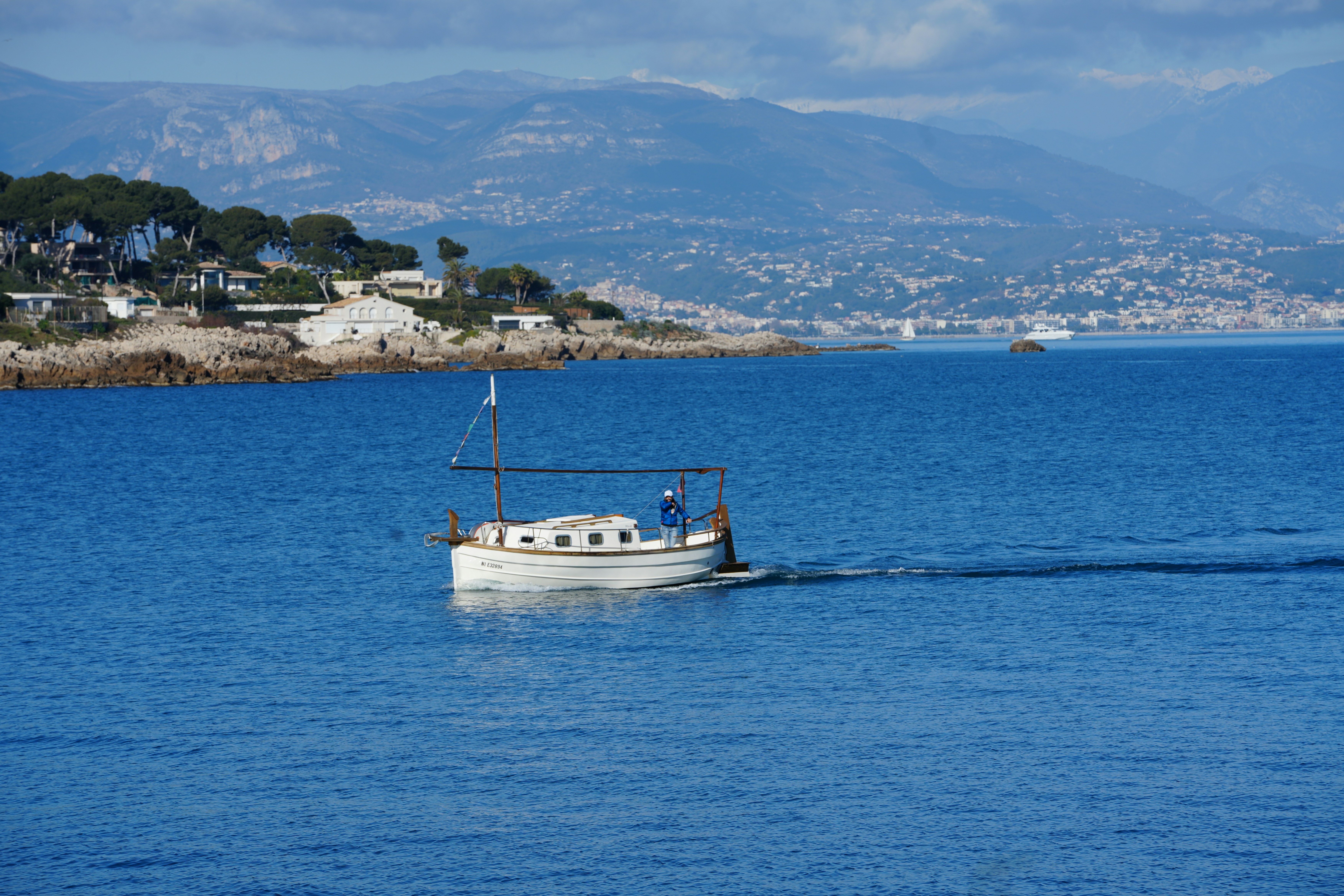 A boat sails on the sea near the coast.