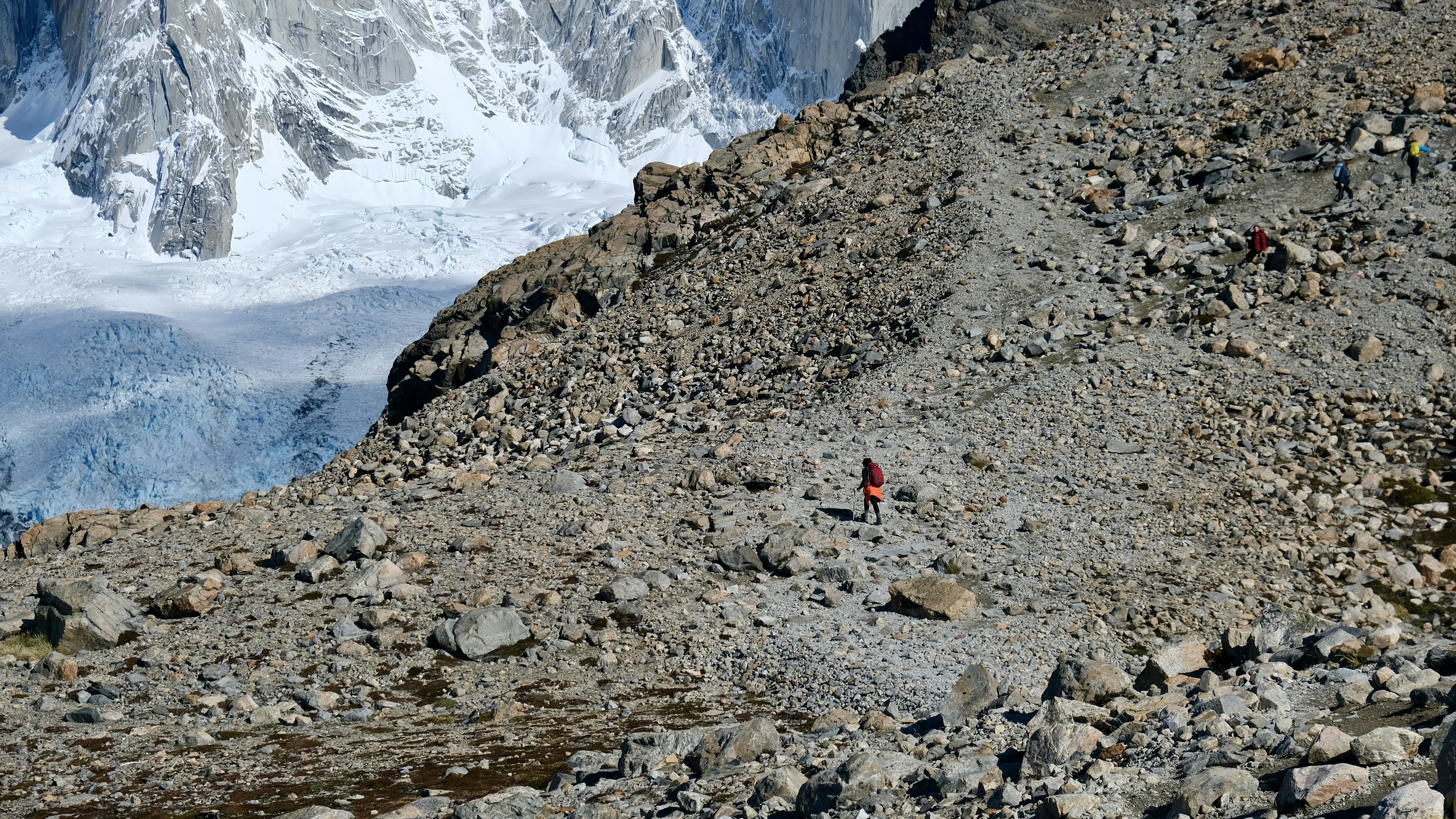 A lone hiker ascends a rocky mountain trail.