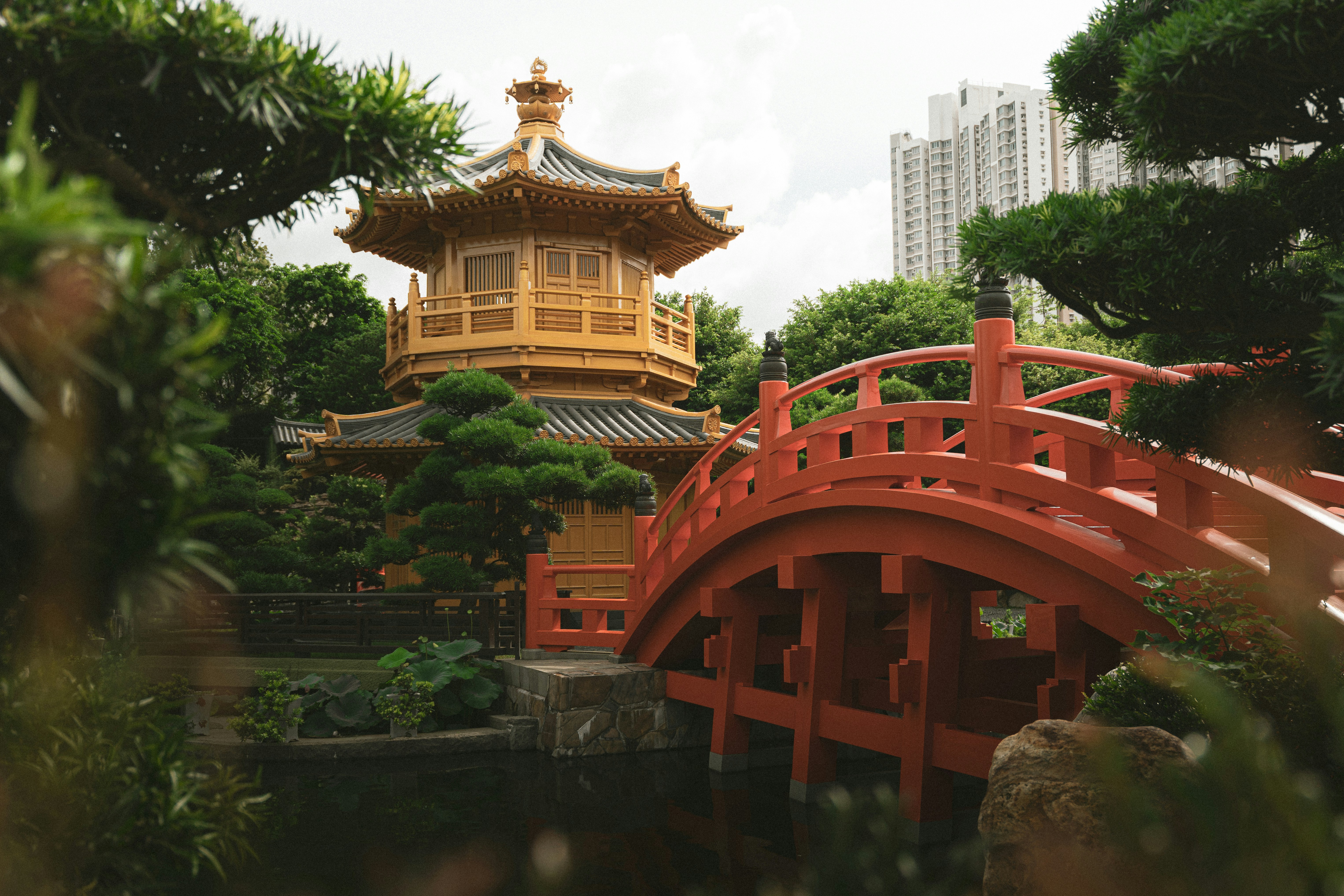 A red bridge leads to a golden temple.
