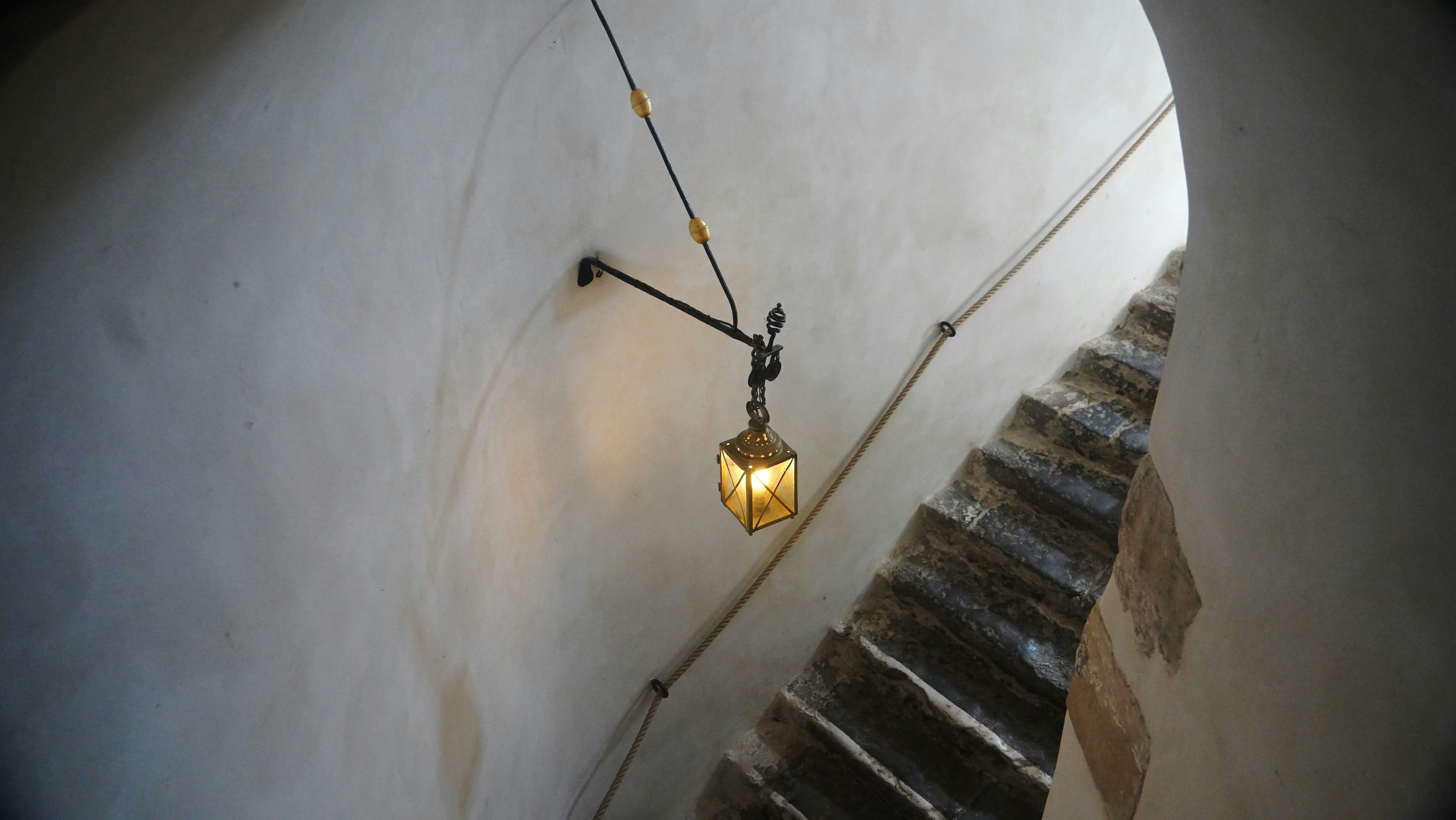 Una linterna ilumina una escalera oscura y estrecha.