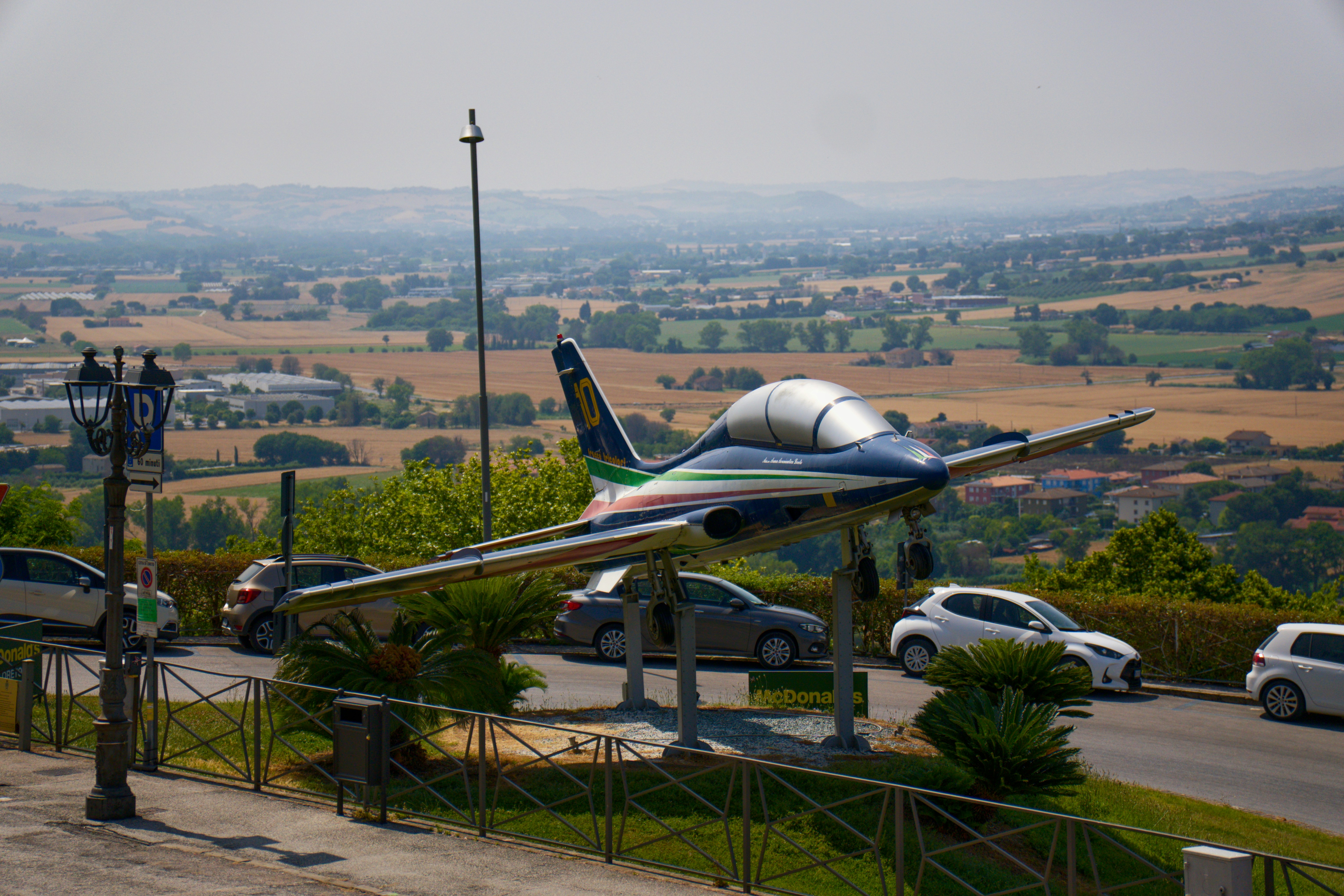 Airplane sculpture overlooks a scenic countryside view.