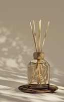 A reed diffuser sits on a wooden plate.