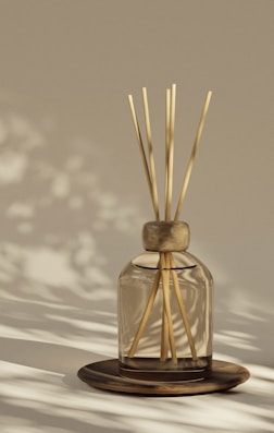 A reed diffuser sits on a wooden plate.