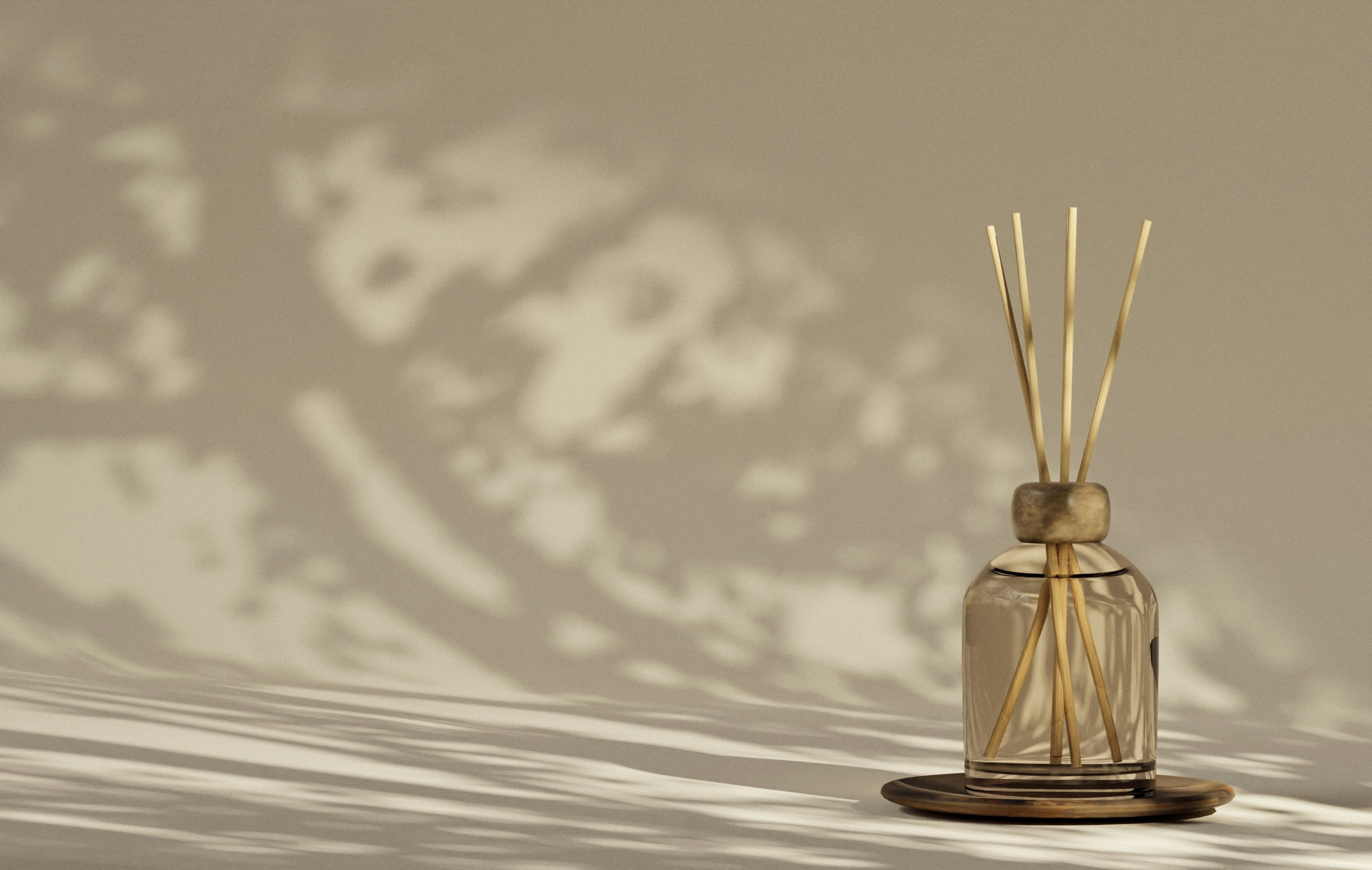 A reed diffuser casts shadows on a neutral background.