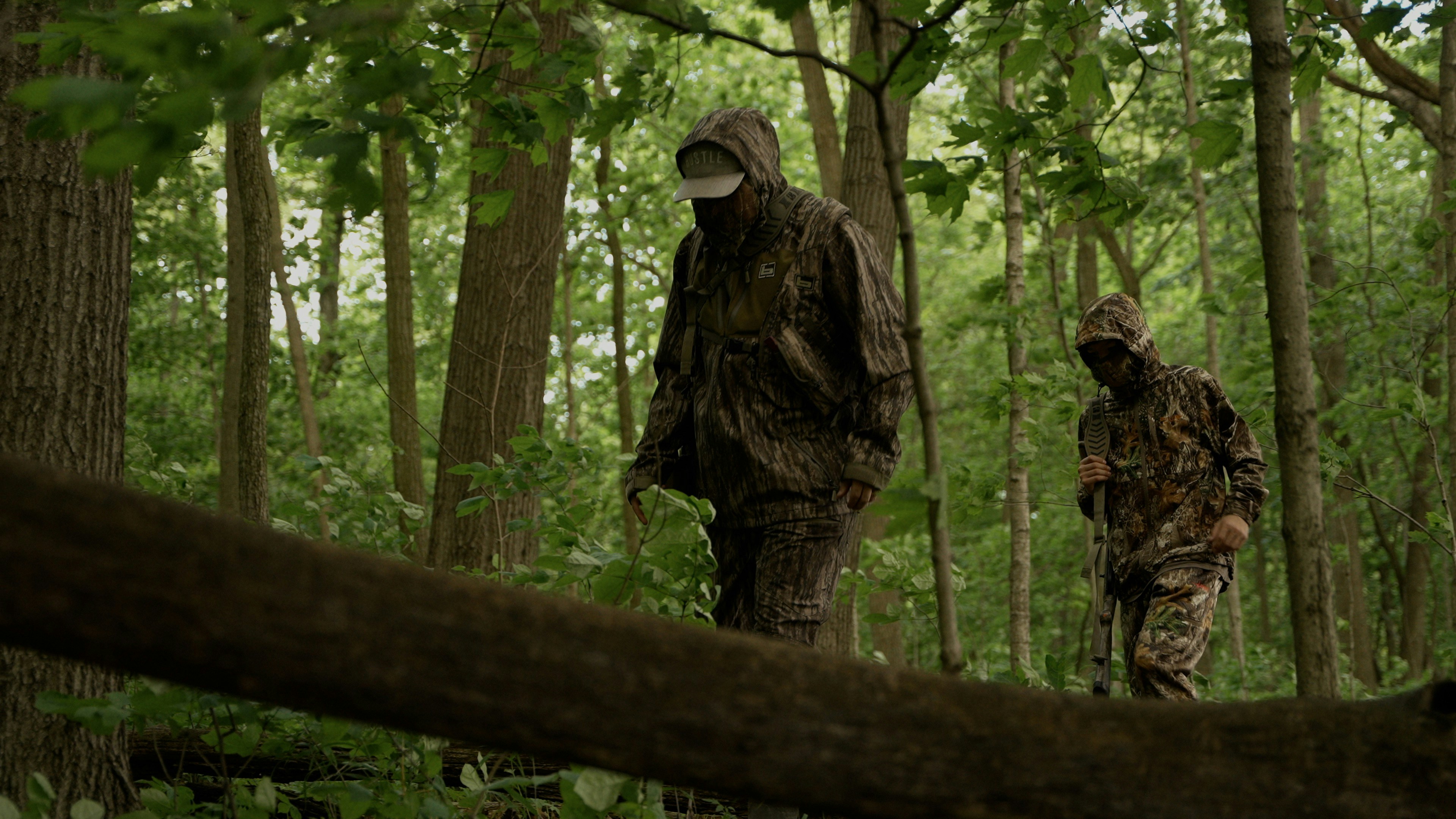 迷彩服を着た2人が森の中を歩きます。