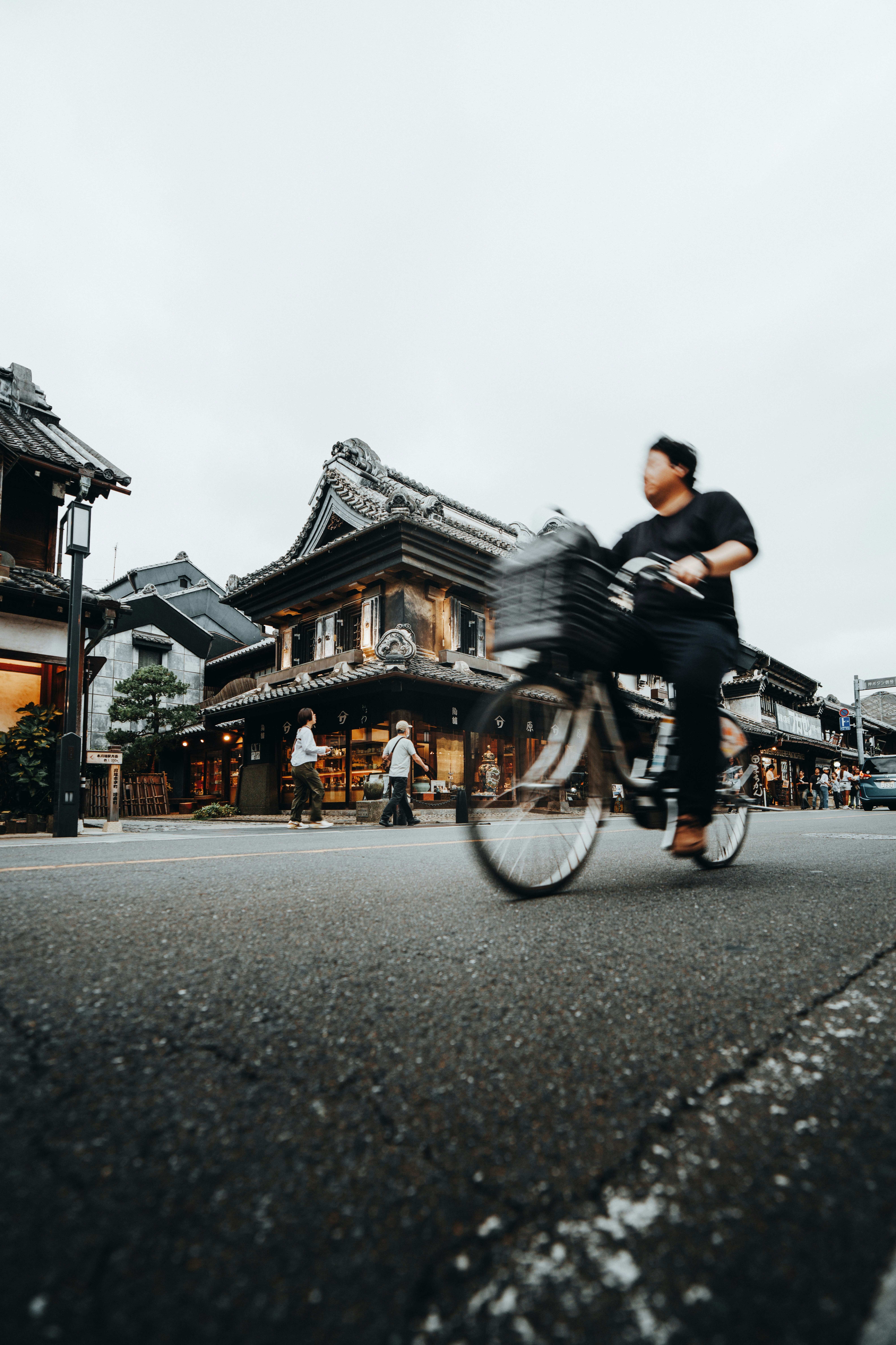 A person rides a bicycle past japanese buildings