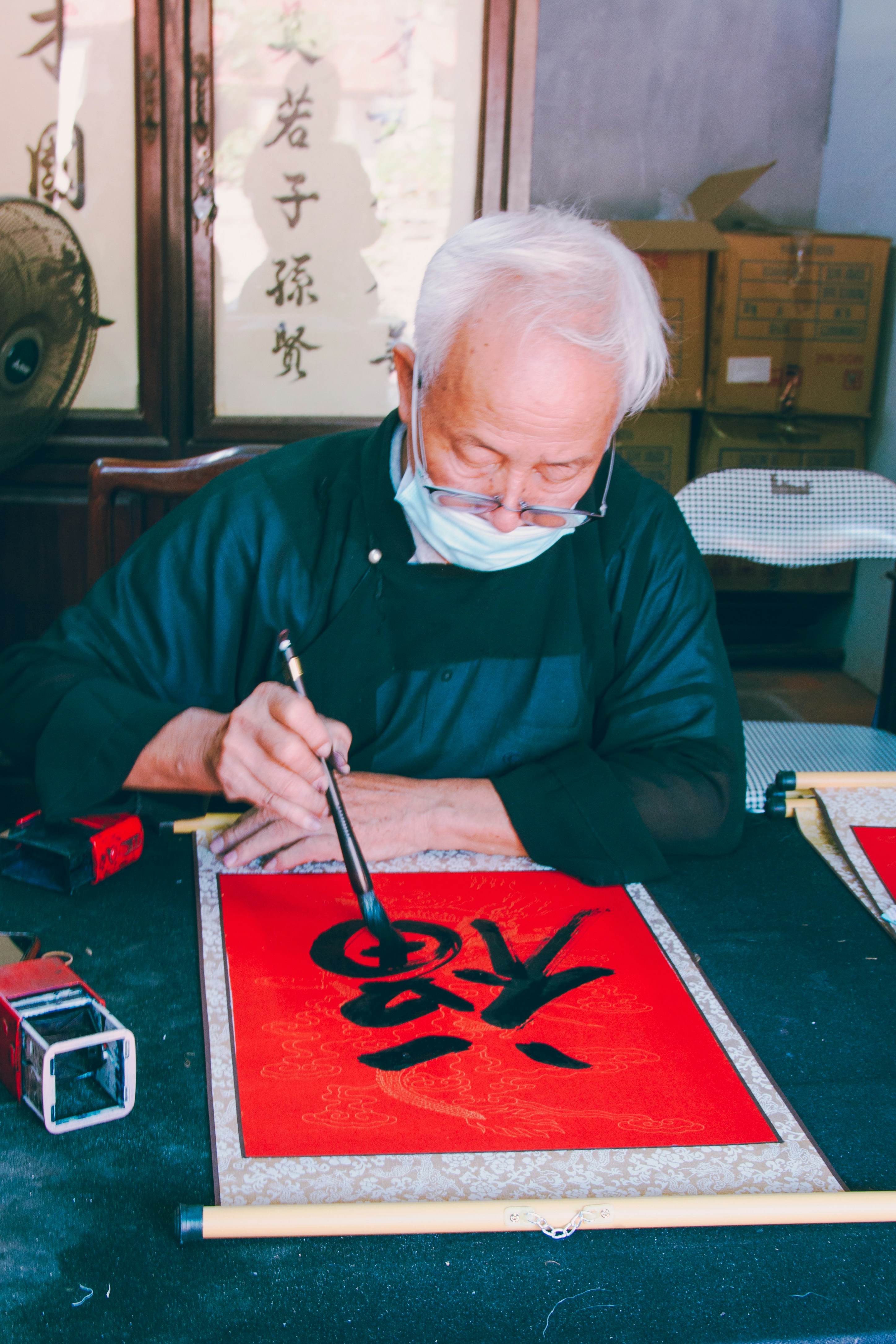 An elder is practicing chinese calligraphy.
