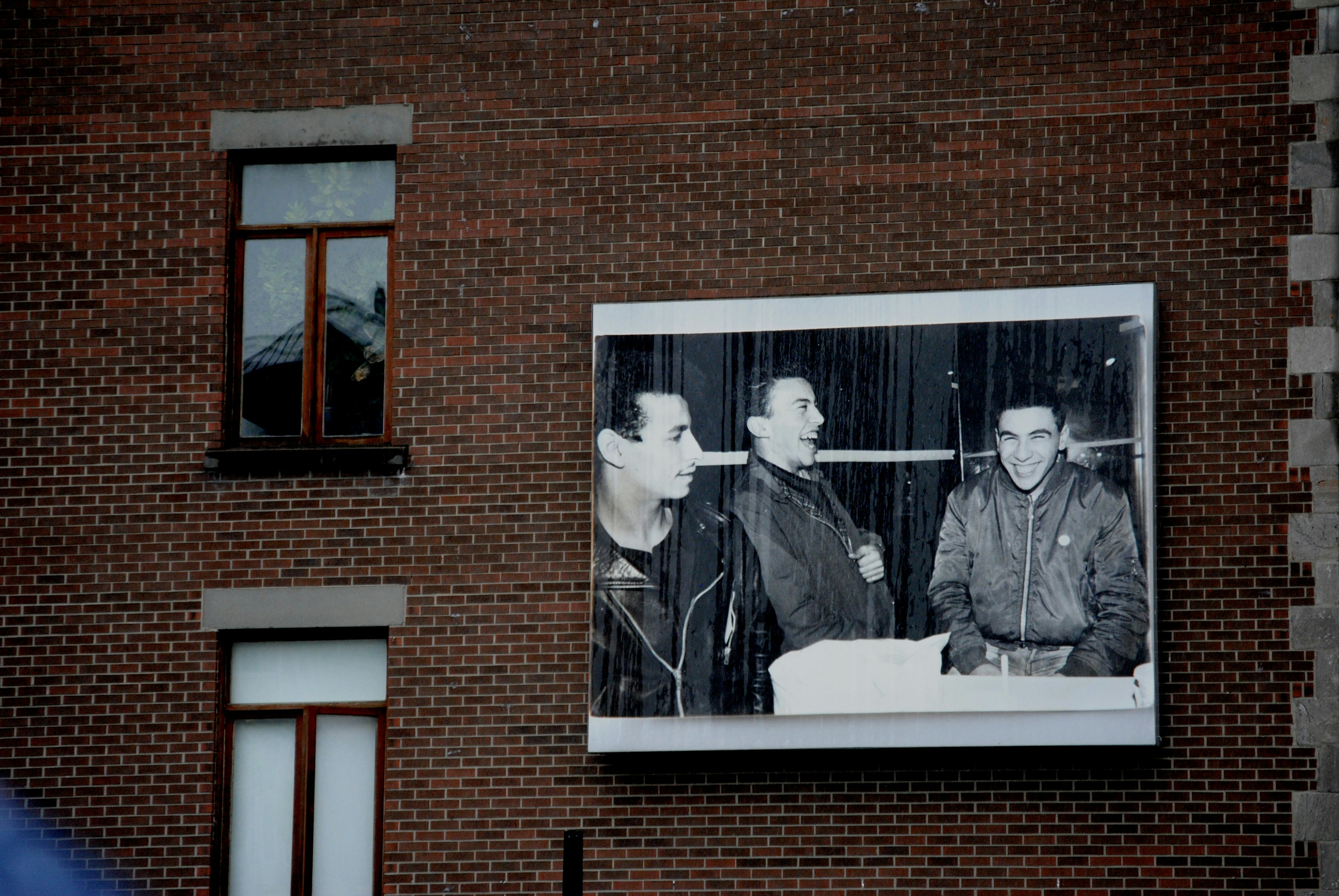 A black and white photo is on a brick wall.