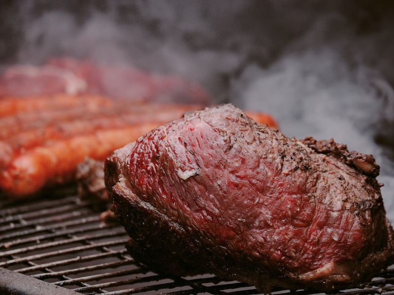 Steak and carrots sizzling on a grill.
