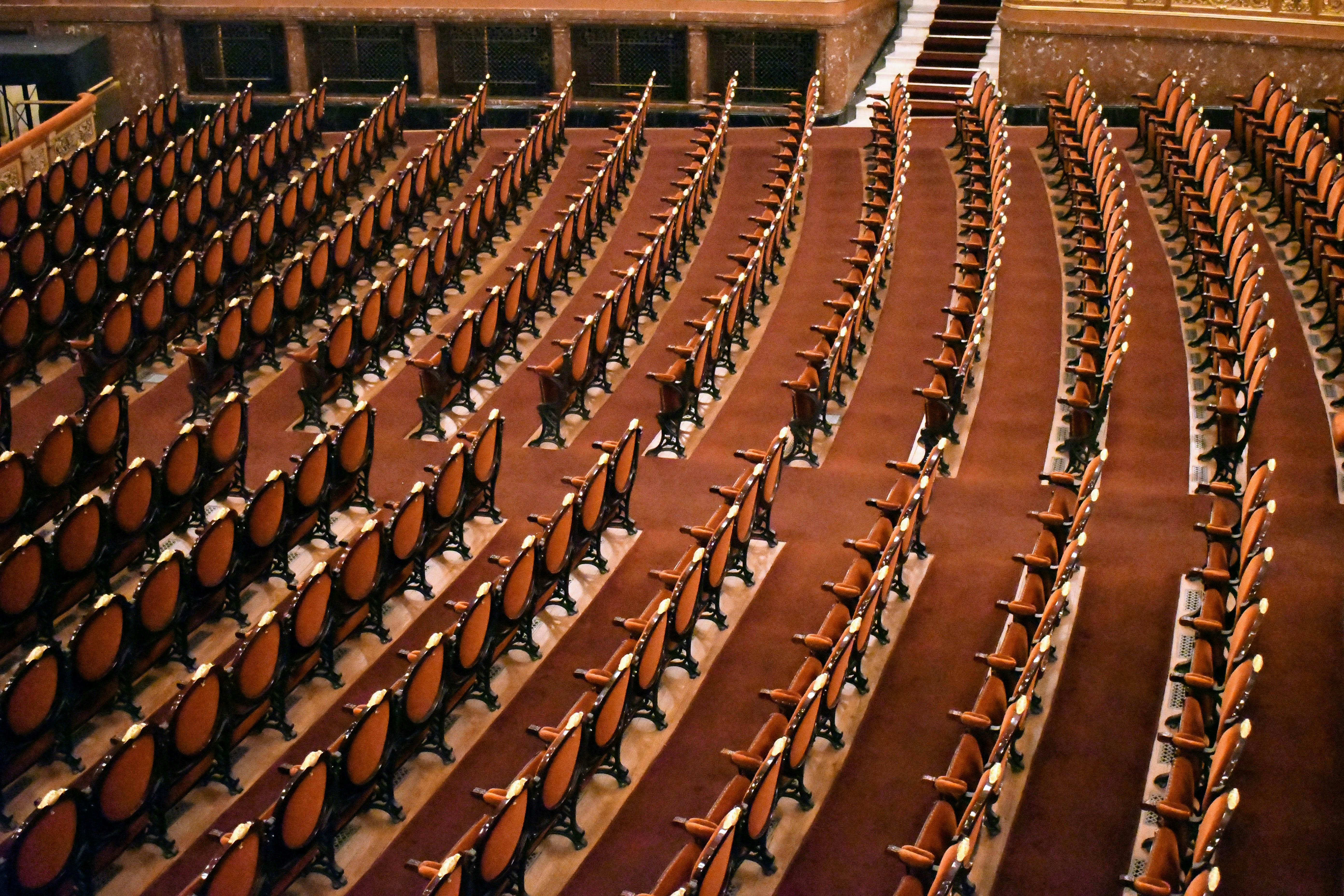 Rows of empty chairs fill a large auditorium.