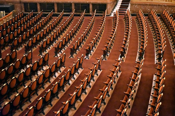 Rows of empty chairs fill a large auditorium.